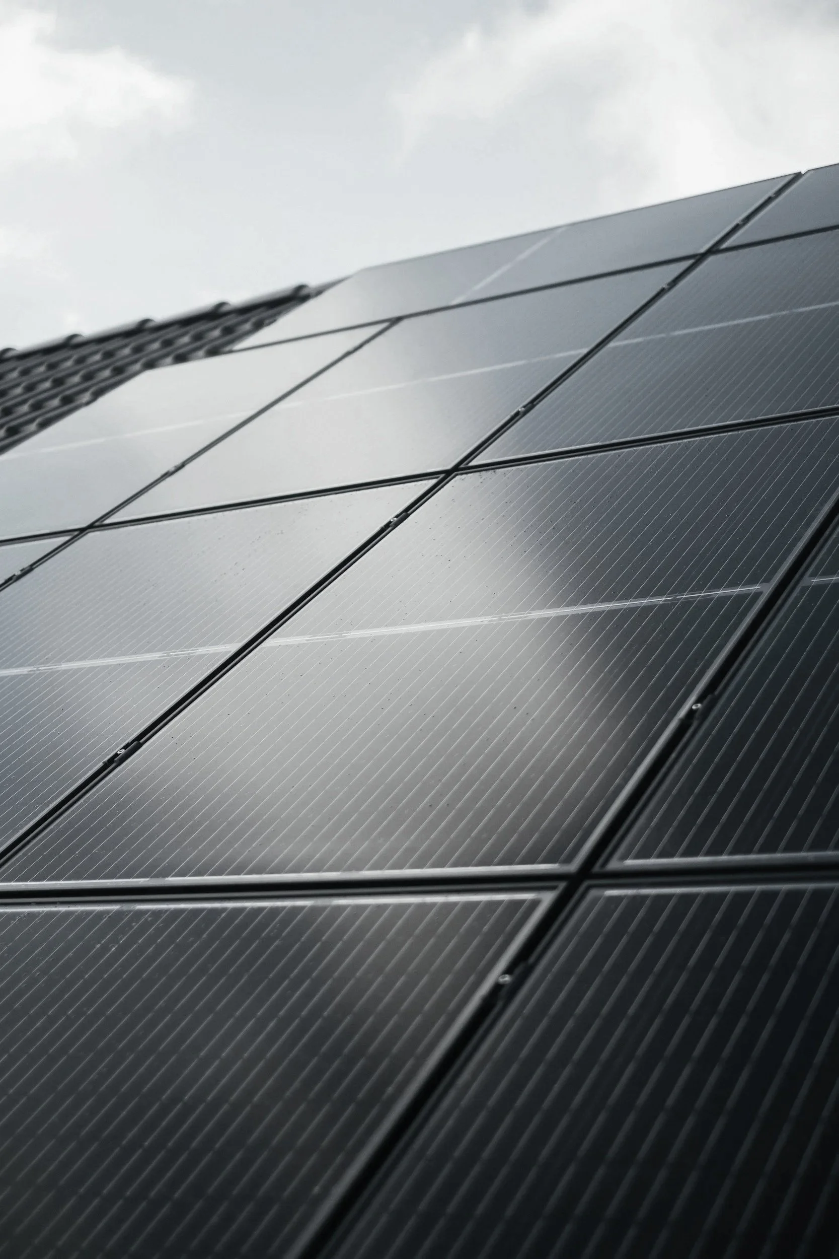 Close-up of solar panels on the side of a building with an overcast sky in the background.