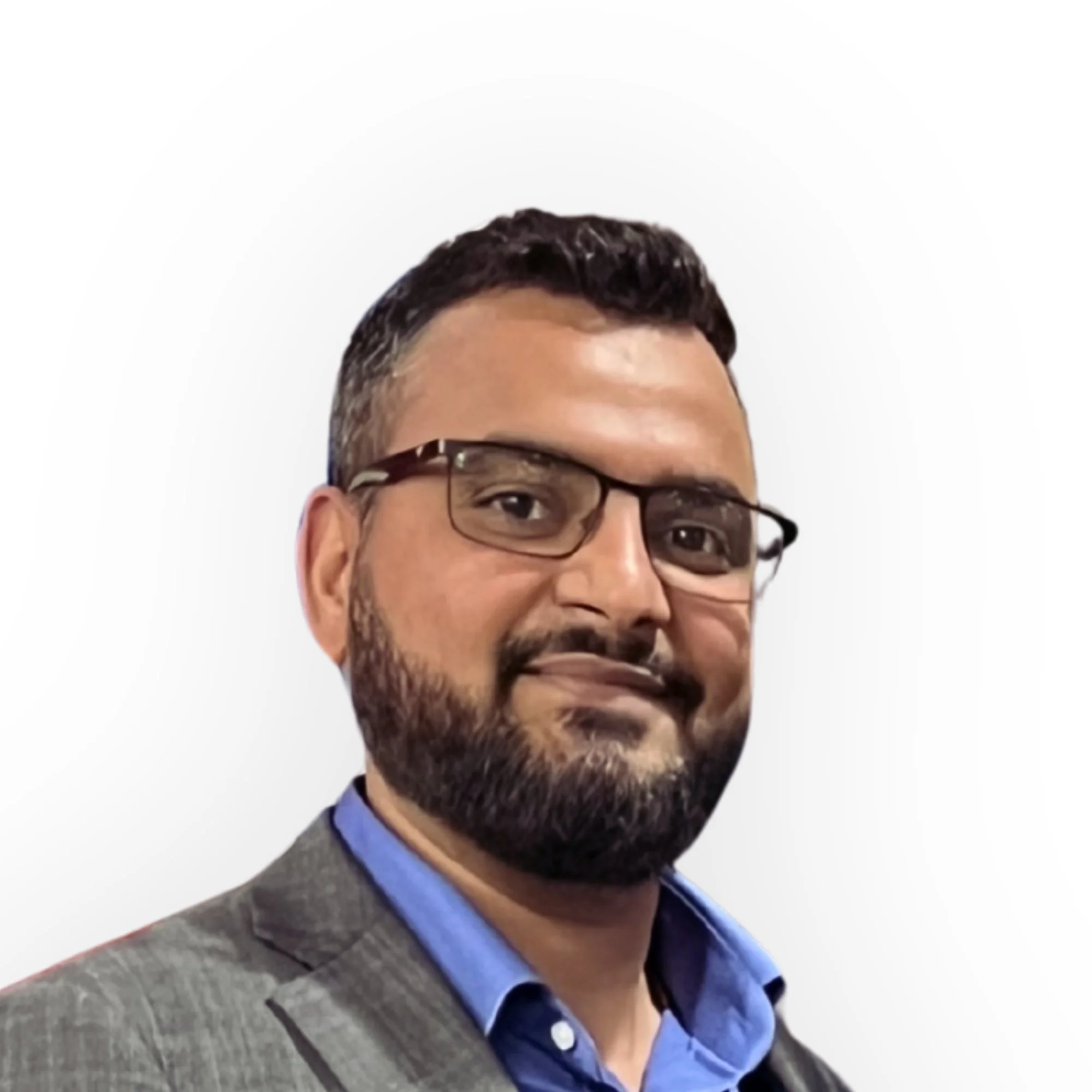 A man with a beard and glasses wearing a gray blazer and blue shirt, smiling against a plain white background.