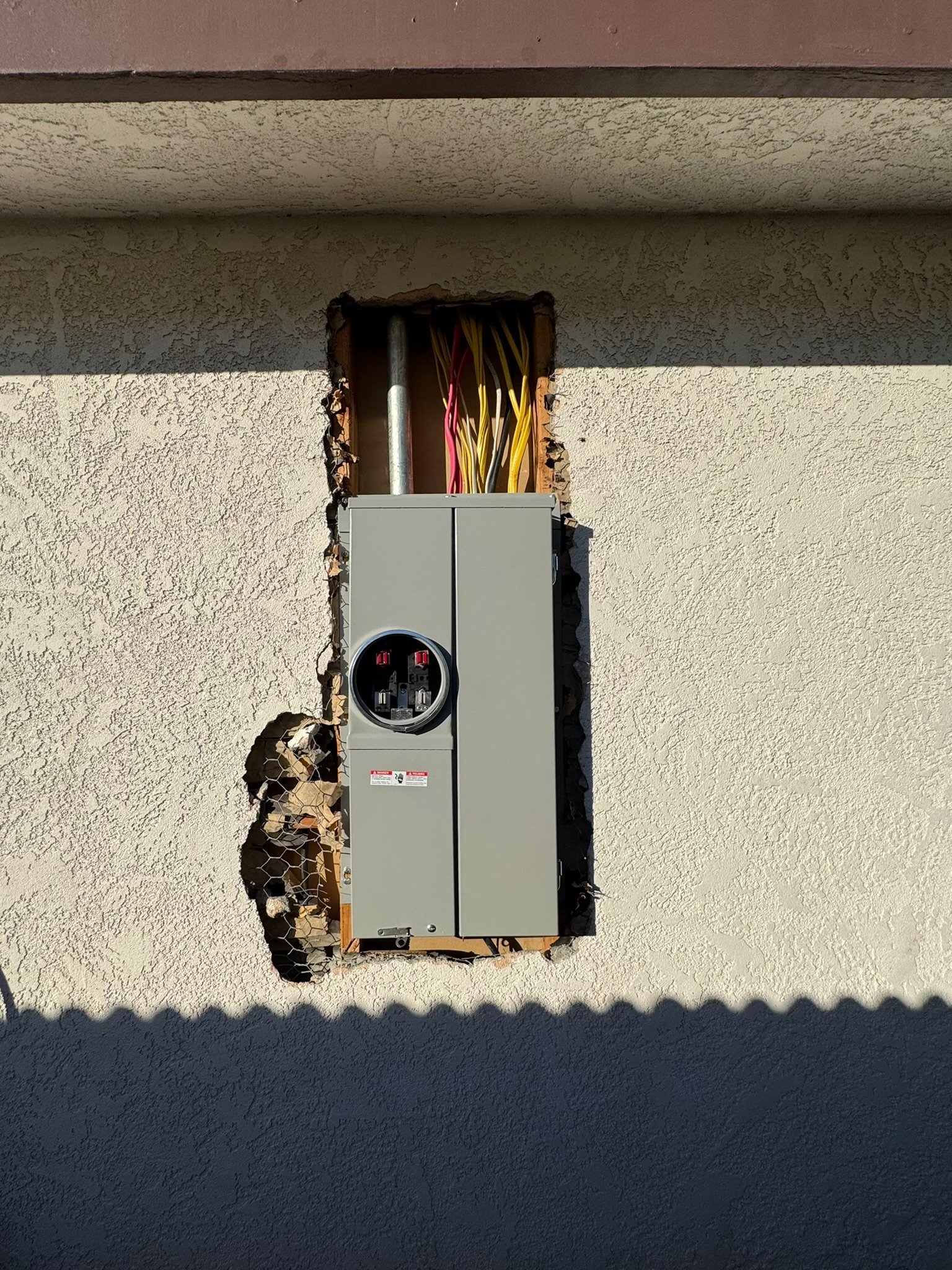 Electrical outlet box with wires installed on the exterior wall of a building under construction or repair.