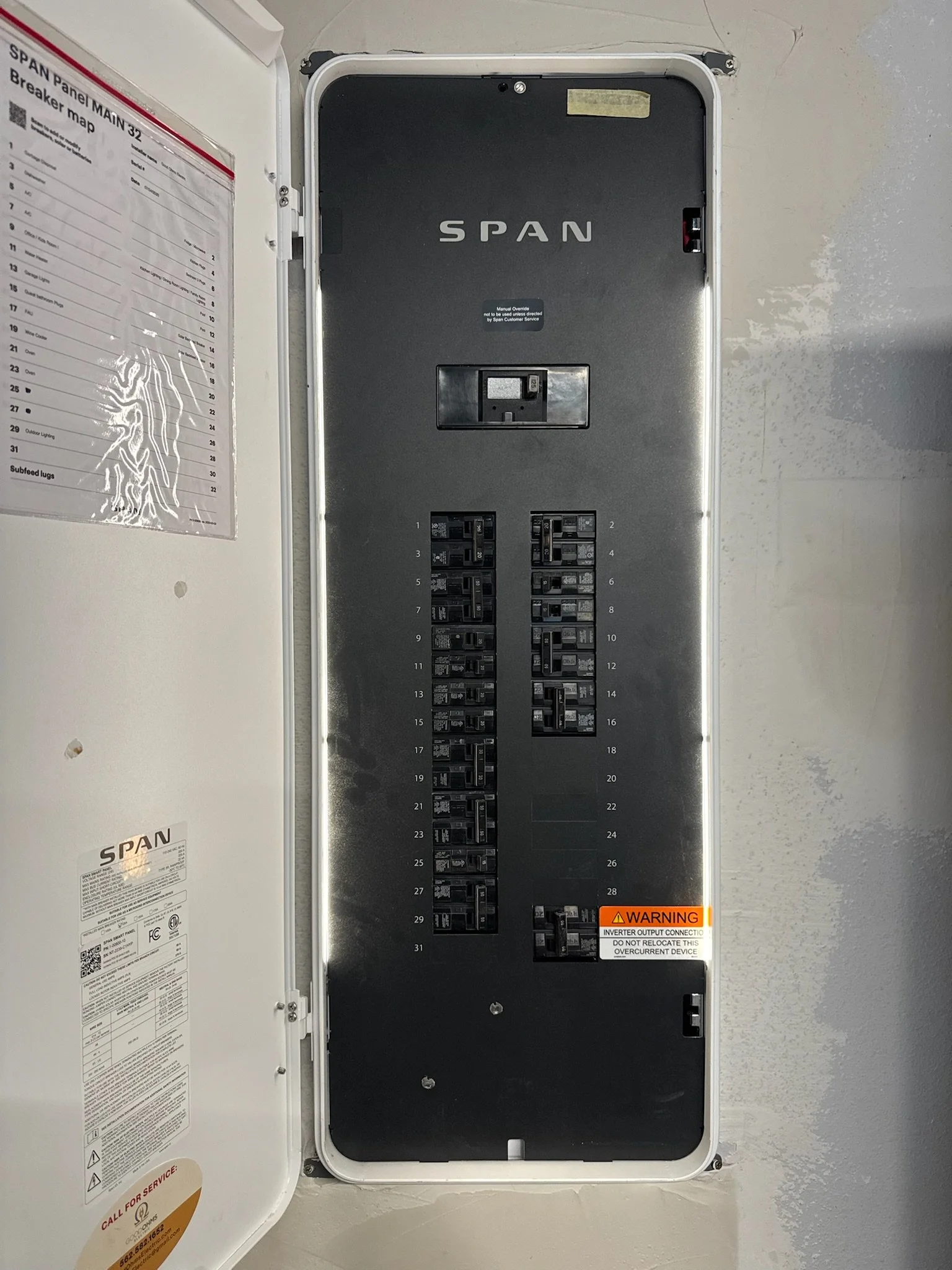 An electrical breaker panel with multiple switches and a warning label at the bottom right corner.
