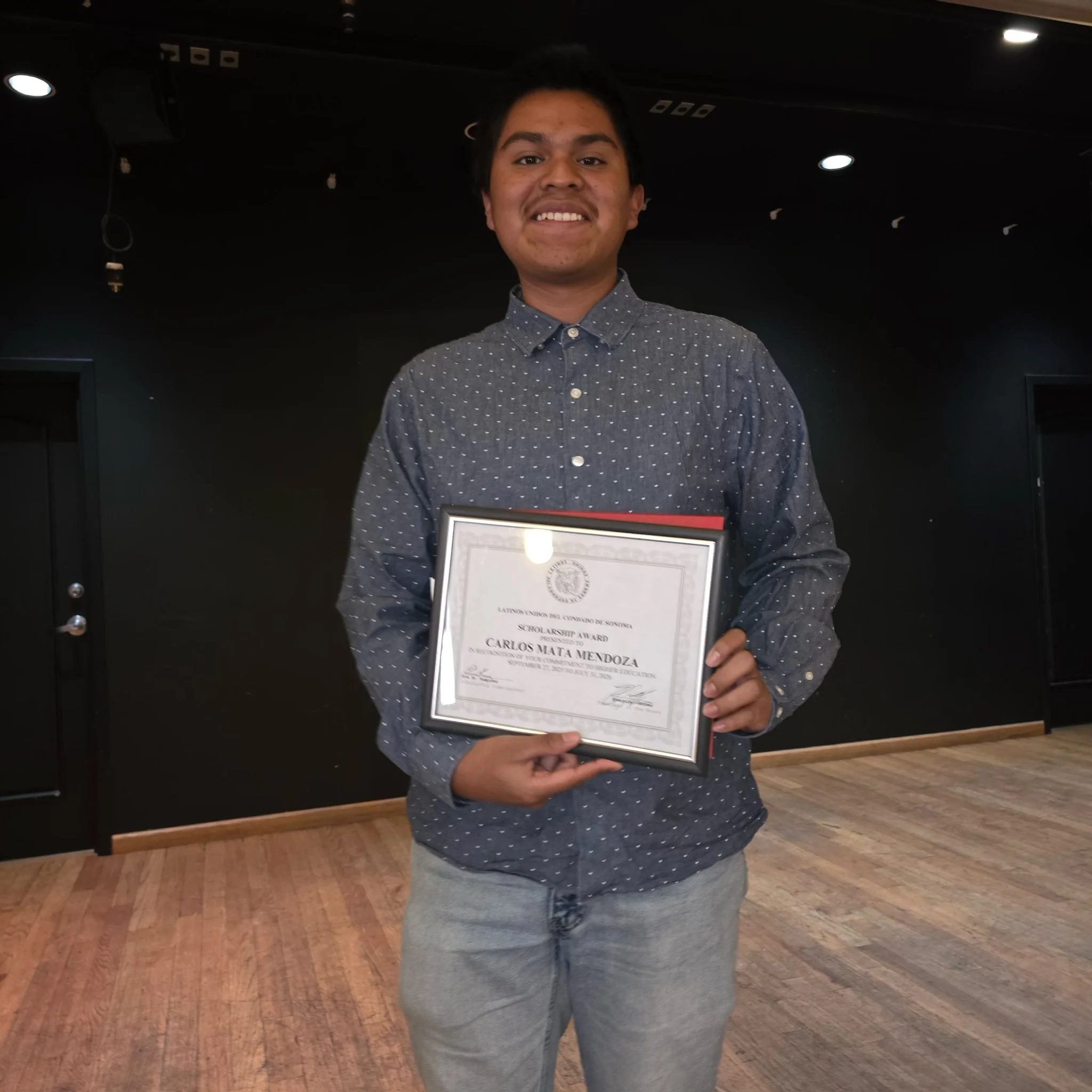 Young man holding a certificate of scholarship award.