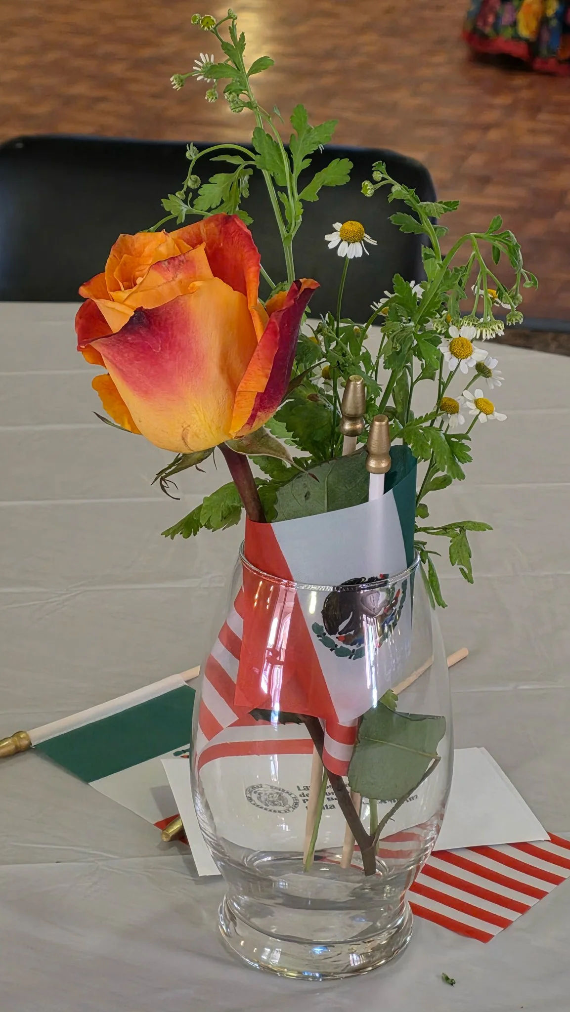 A small flower arrangement on a table, decorated with an Mexican flag.