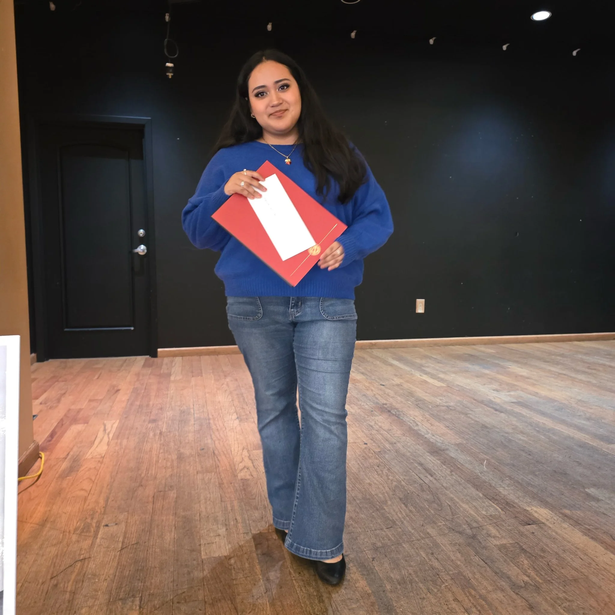 A woman standing on stage holding scholarship award