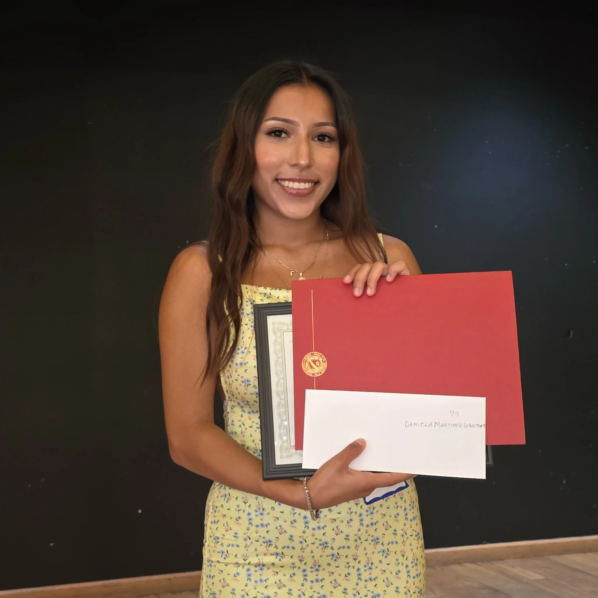 A woman holding a scholarship award on stage.