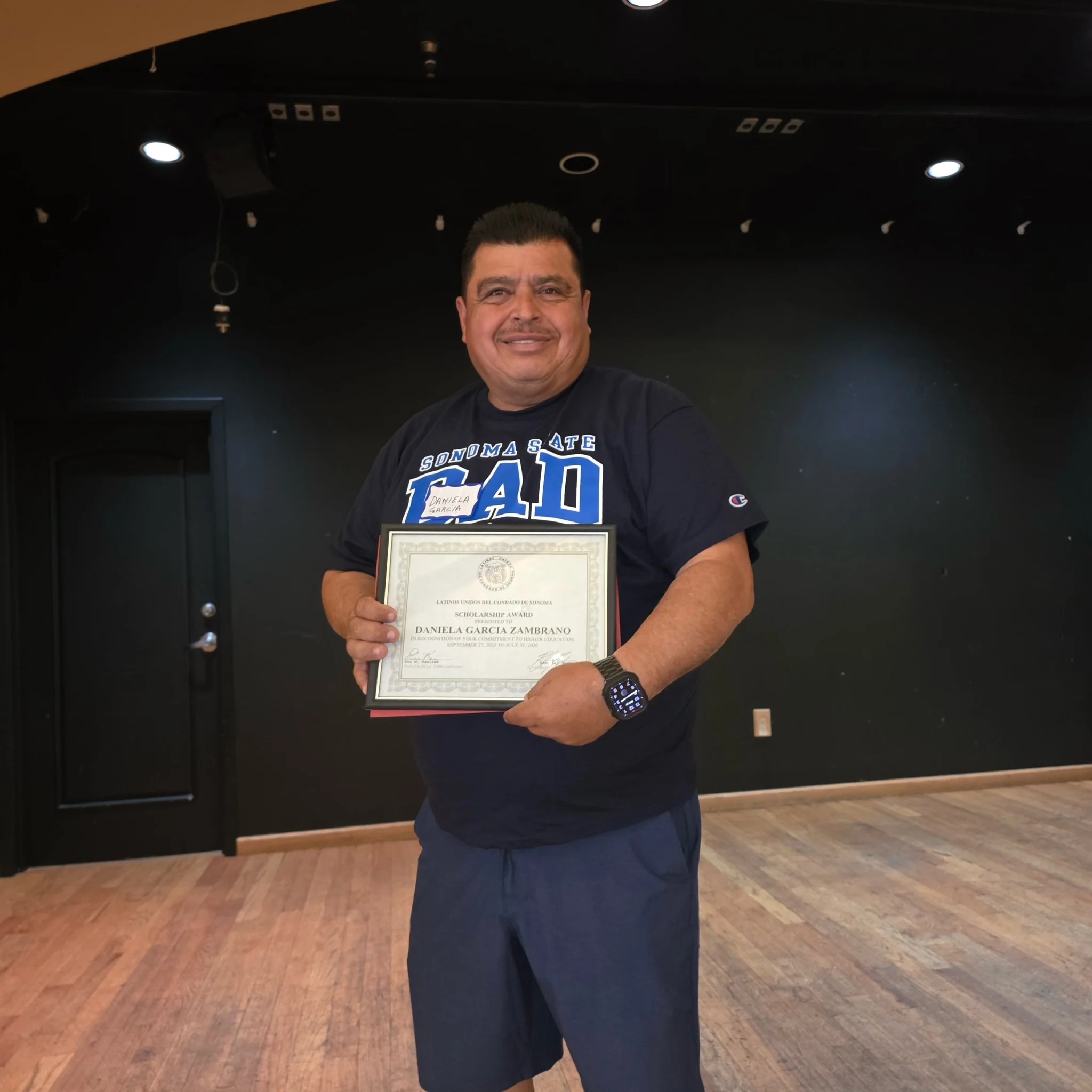 A man holding a scholarship award on stage.