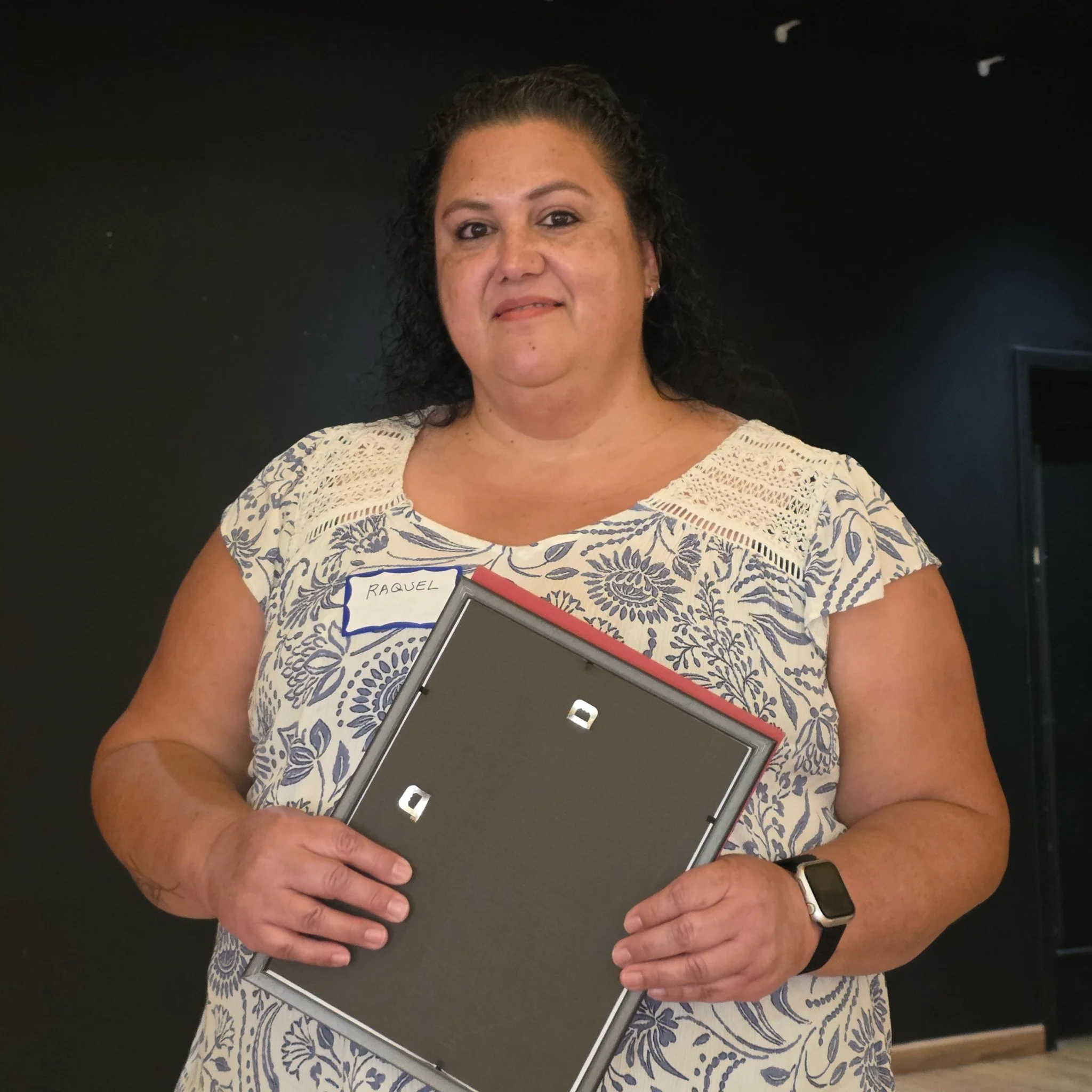 A woman holding a certificate of scholarship award.