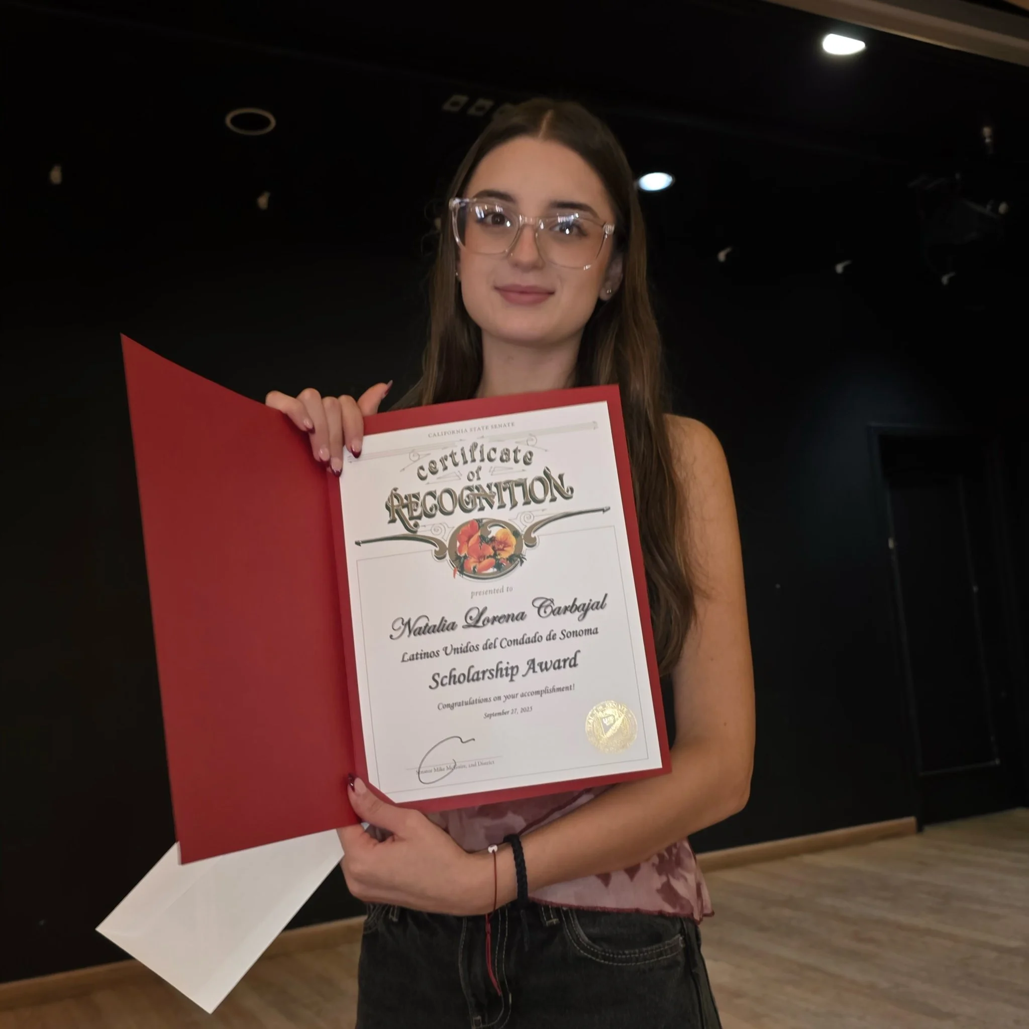 Young woman holding a certificate of scholarship award.