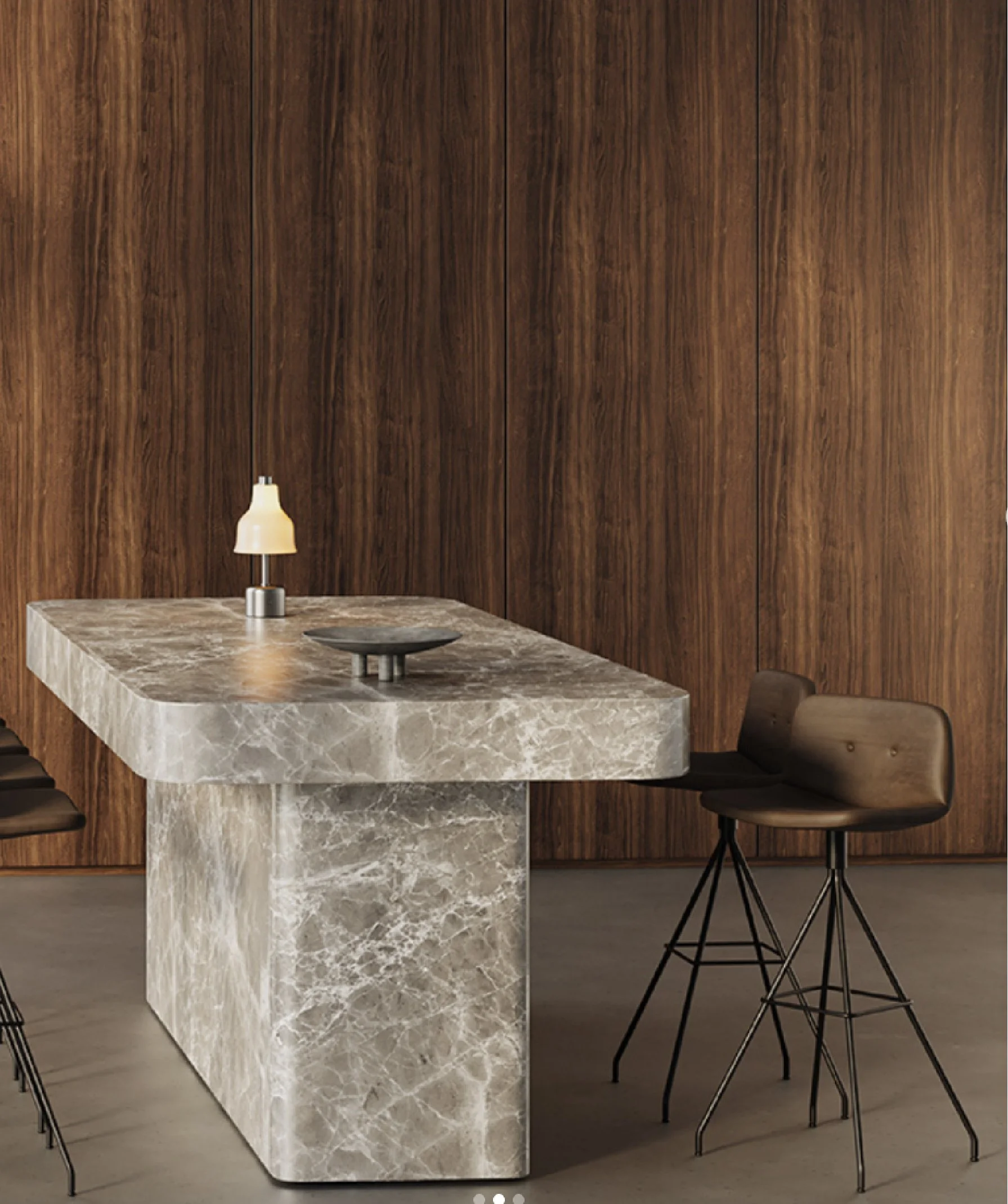 Indretning med et rundt, beige marmorbord, to barstole med lædersæder og metalben, vægge beklædt med mørkt træ.