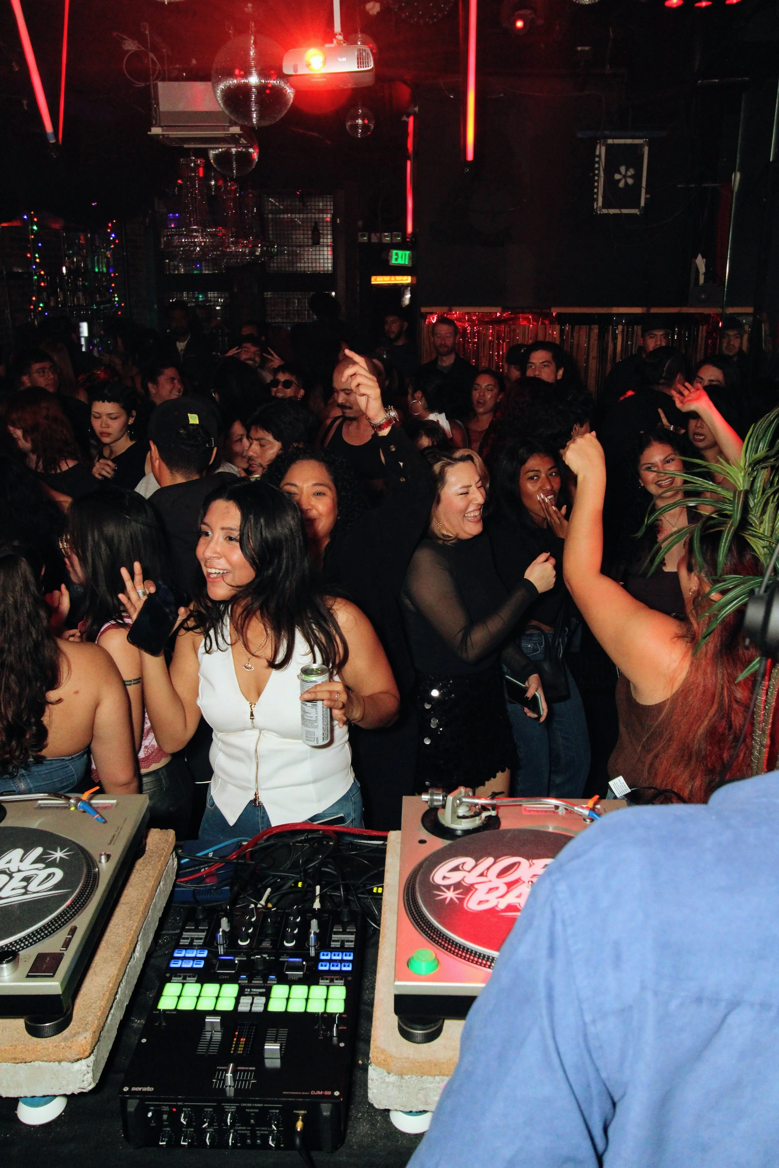 People dancing and enjoying music at a nightclub with DJ equipment in the foreground.