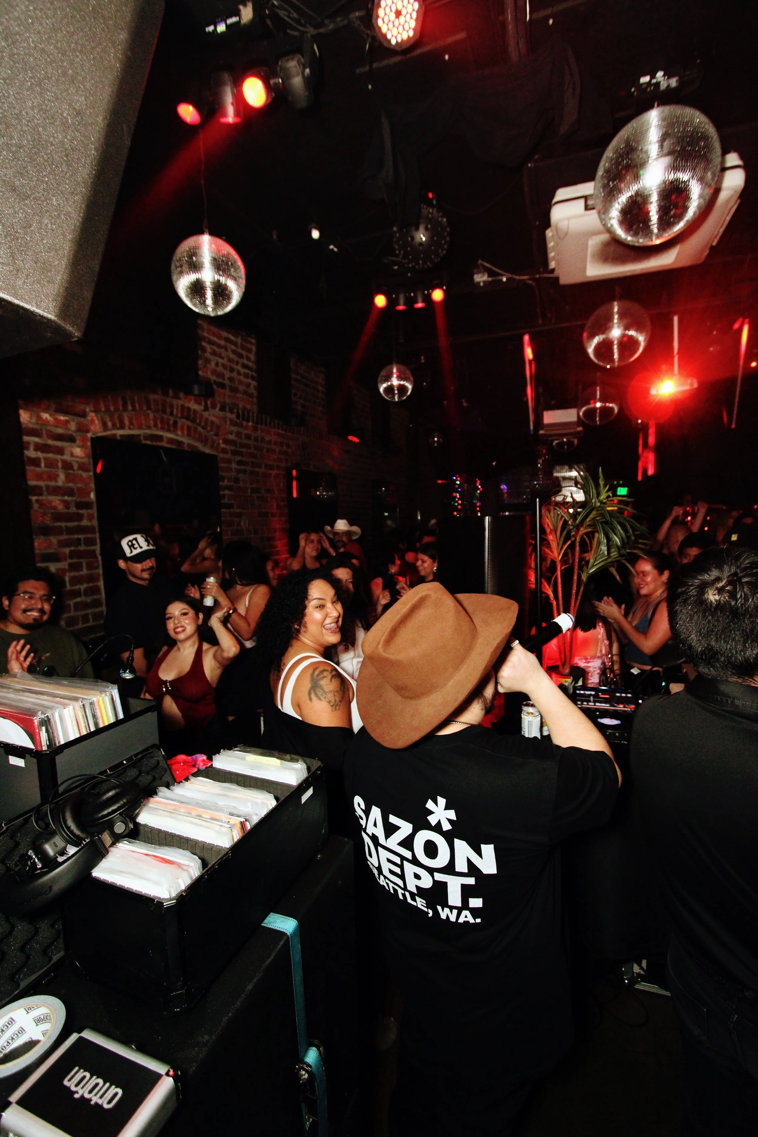 People dancing and enjoying music at a nightclub with disco balls and red lighting.