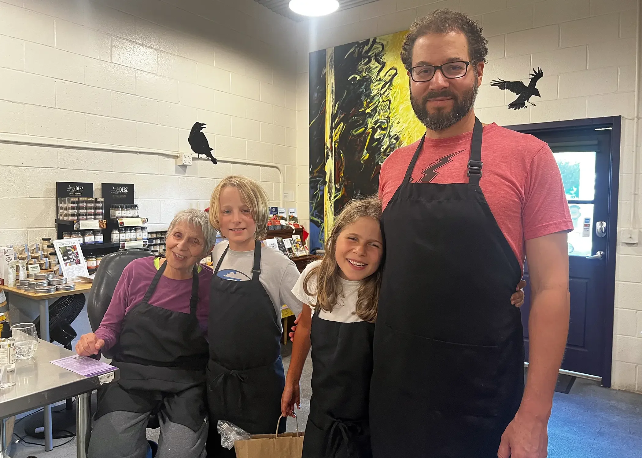 Two adult and two youth volunteers wearing black aprons hug