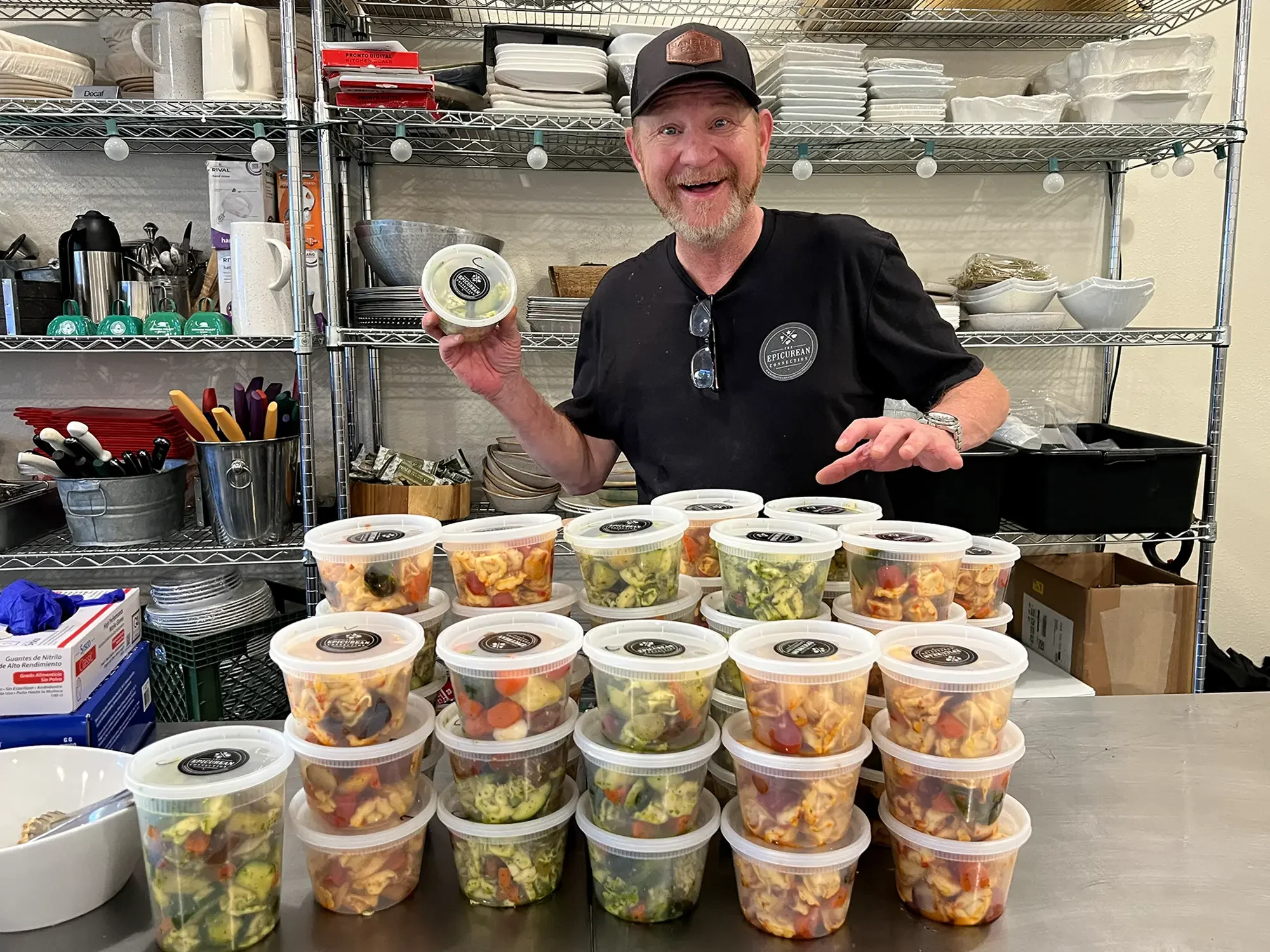 Ben Sessions poses with ready to eat, pre-made meals in the kitchen
