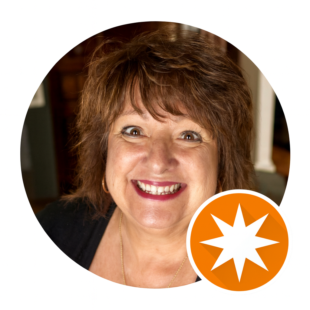 A smiling middle-aged woman with short, wavy brown hair and light makeup, wearing a black top and jewelry, in an indoor setting with a blurred background.