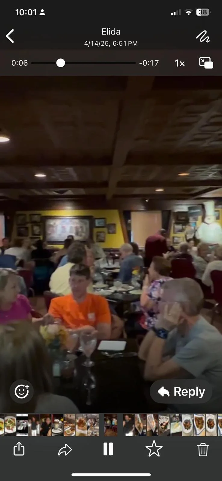 People dining at tables in a restaurant with yellow walls and framed pictures.