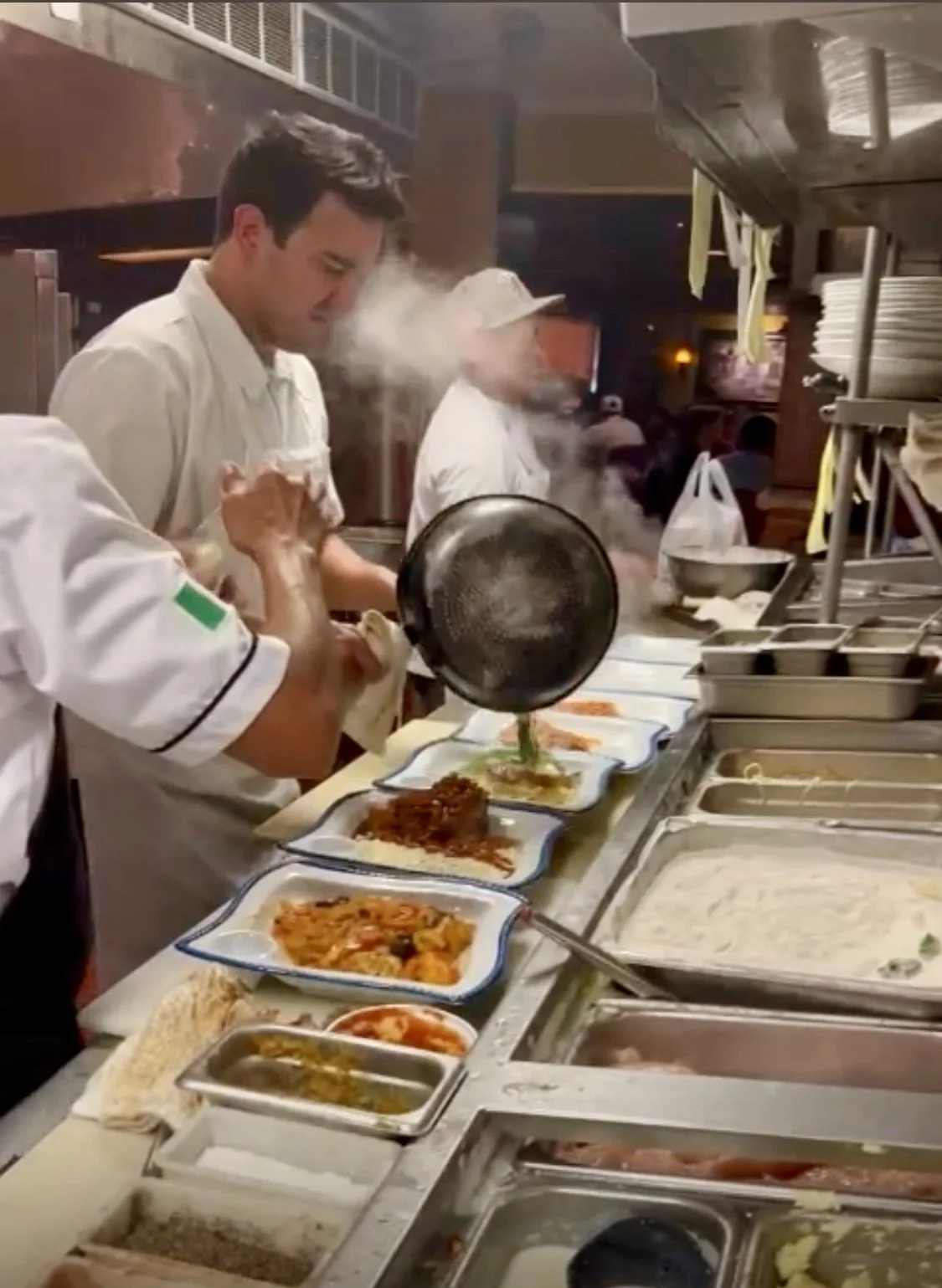 Chefs preparing and serving dishes at a busy restaurant kitchen.