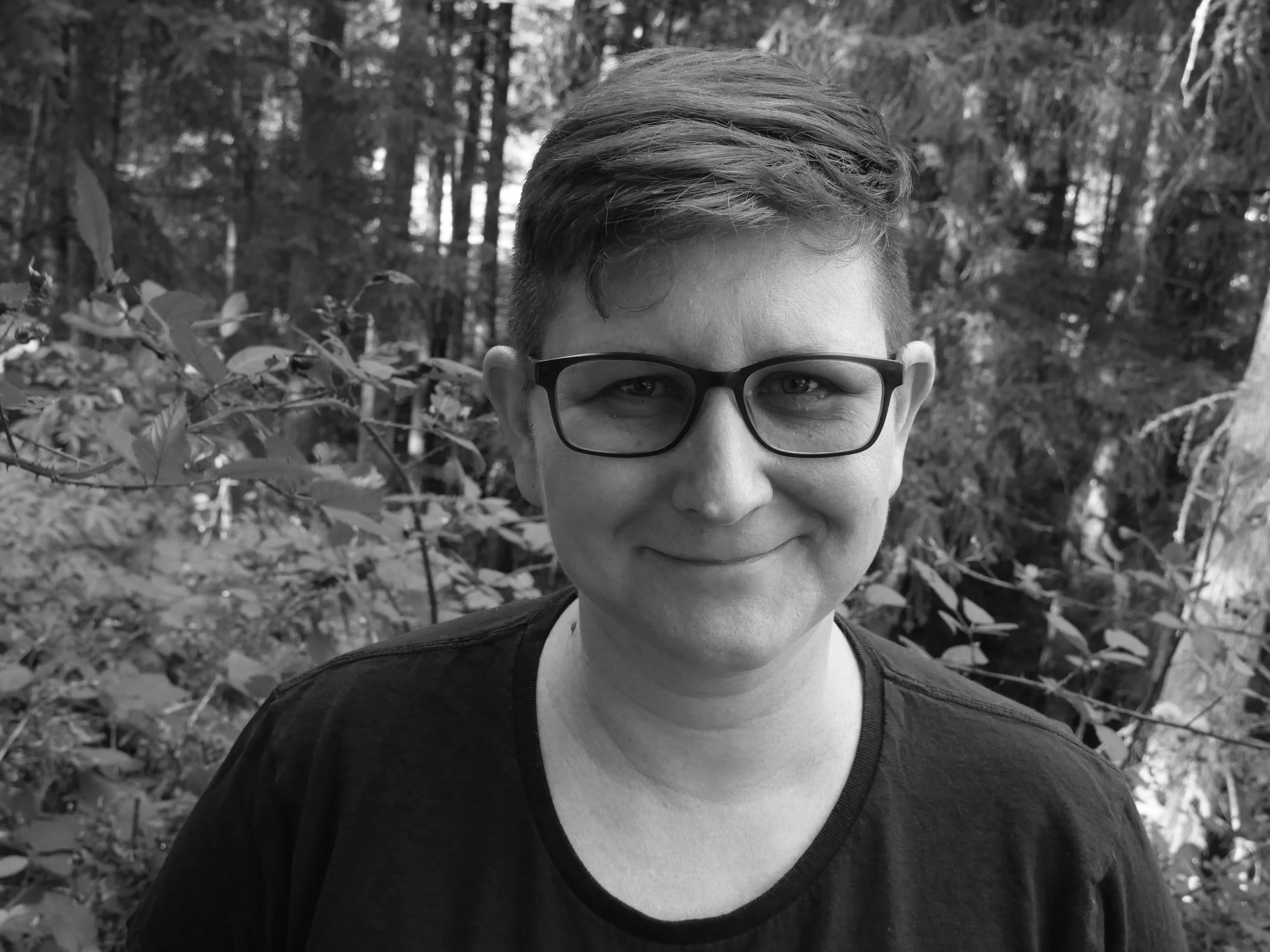 Chelsea, smiling outdoors in a wooded area, black and white photograph.