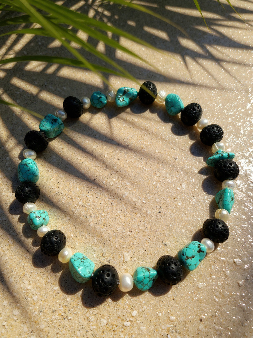 Turquoise, baroque pearls, and textured lava rock beads, finished in sterling silver and adjustable with a two-inch chain extender.