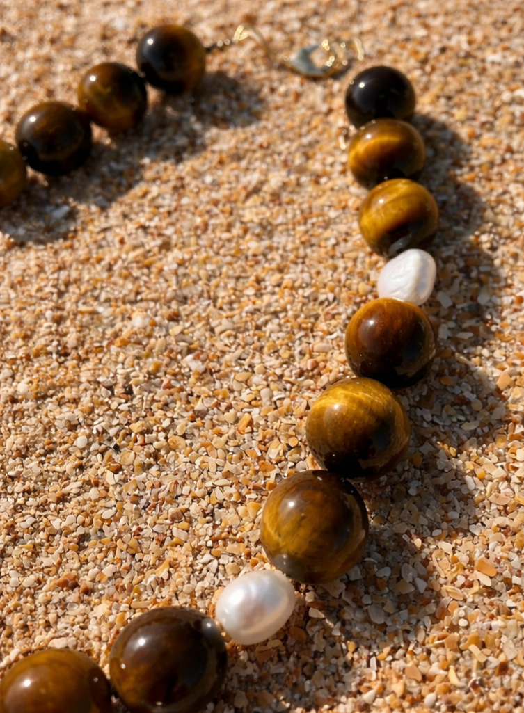 Large tiger’s eye beads paired with baroque freshwater pearls, finished with 18k gold-plated accents and a two-inch chain extender.
