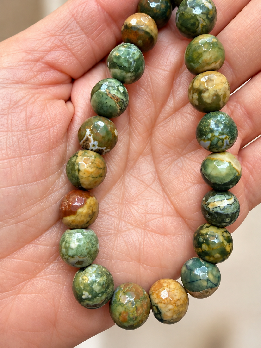 Hand+Holding+Earth-Toned+Gemstone+Beads.png