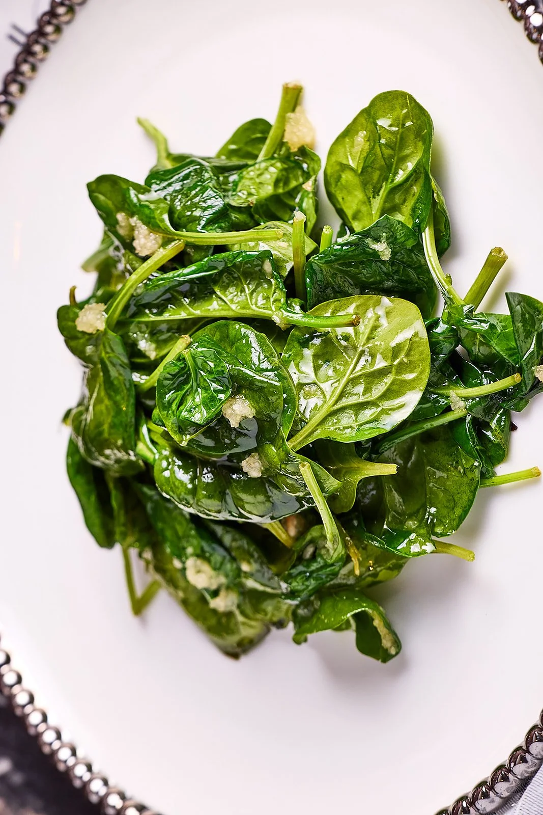 Fresh spinach leaves on a decorative white plate.