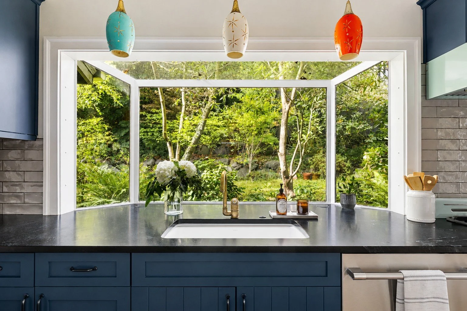 Kitchen garden window nook with teal cabinetry and hanging glass pendant lights, Madrona Craftsman renovation