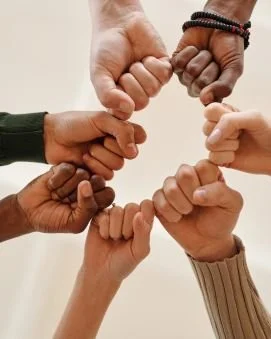 Six diverse hands forming a heart shape with their fists.