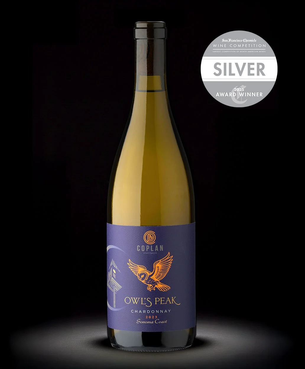 A bottle of Owl's Peak Chardonnay wine from Coplan Vineyards, Sonoma Coast, with a silver award badge indicating '2025 Award Winner' at the San Francisco Chronicle Wine Competition.