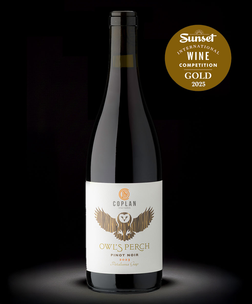 A dark glass bottle of Coplan Vineyards Owl's Perch Pinot Noir wine with a white label featuring a gold-colored owl illustration, and a gold award sticker indicating a 2025 Sunset International Wine Competition Gold medal.