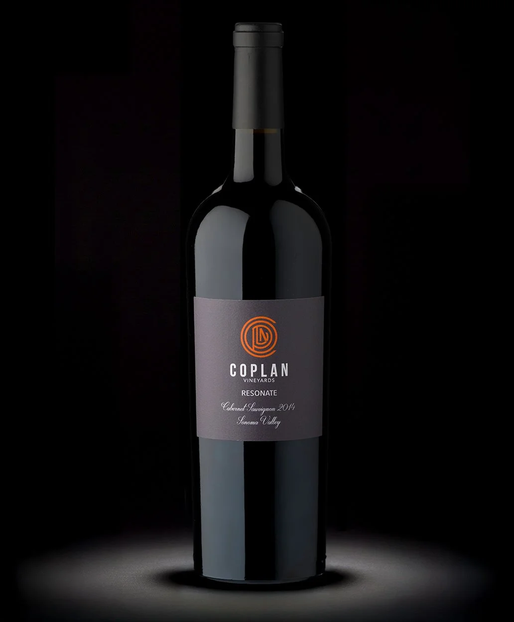 A dark glass bottle of Coplan Vineyards Resonance Cabernet Sauvignon 2014 wine against a black background.