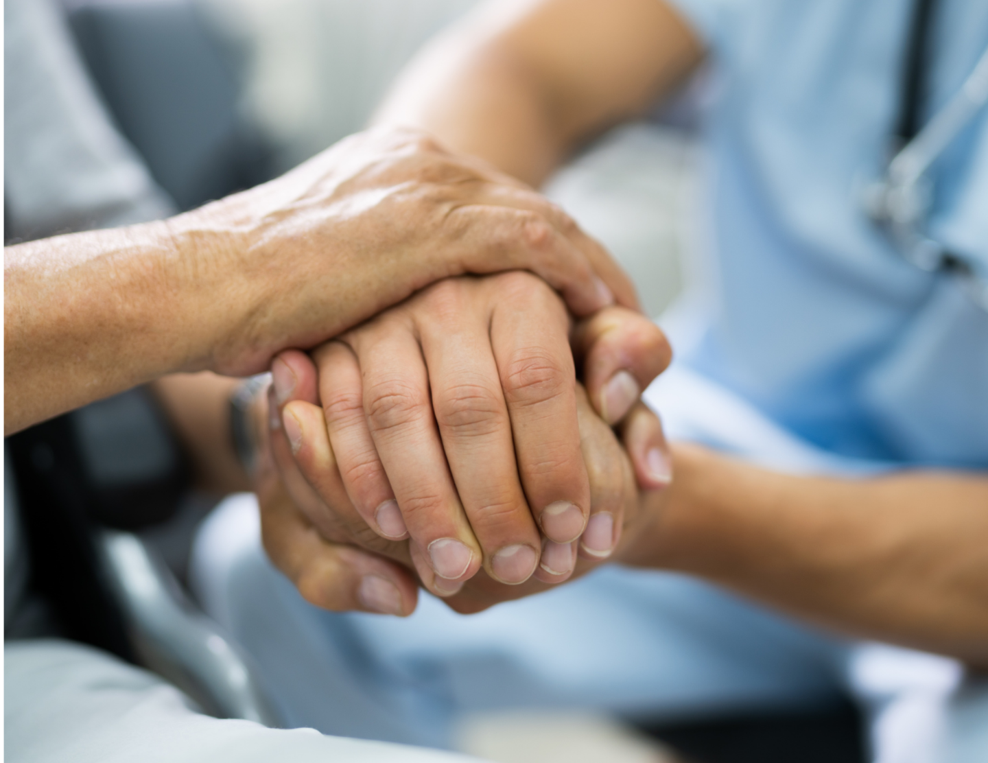 Two hands, one elderly and one middle-aged, clasped together in support.