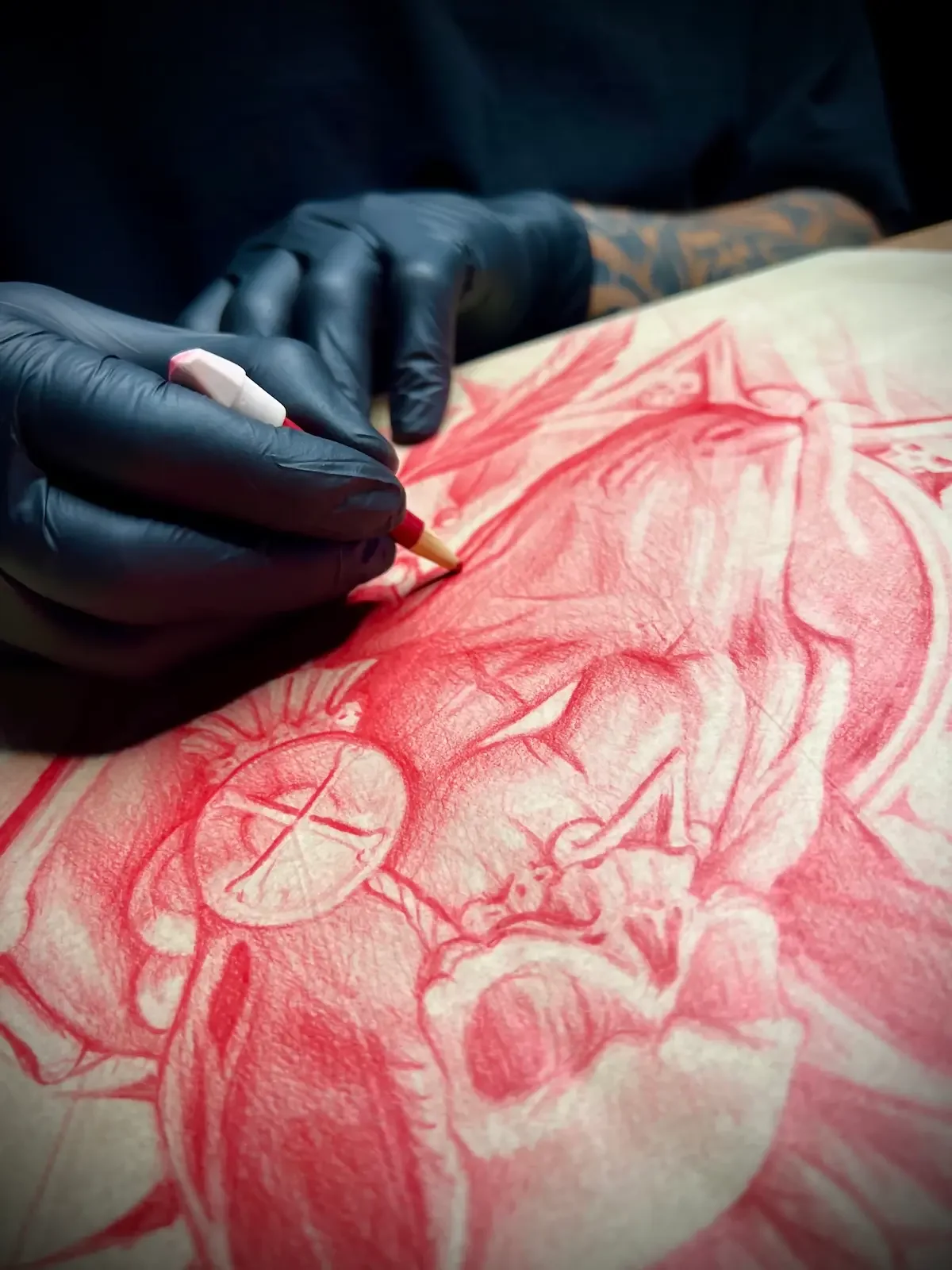 Johny Vasquez tattooing with red ink on skin wearing black gloves in Austin
