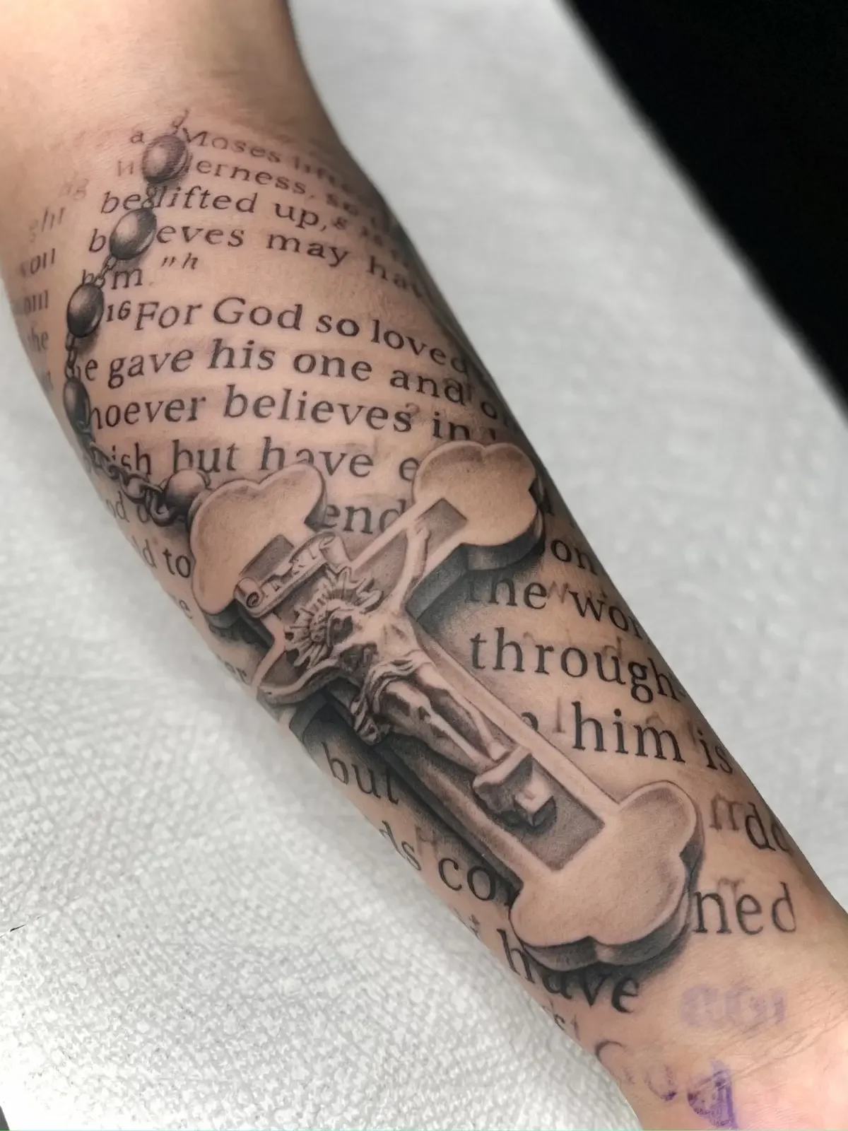 Black and grey religious crucifix with scripture and rosary arm tattoo by Johny Vasquez - Mommasboy Tattoo Austin TX