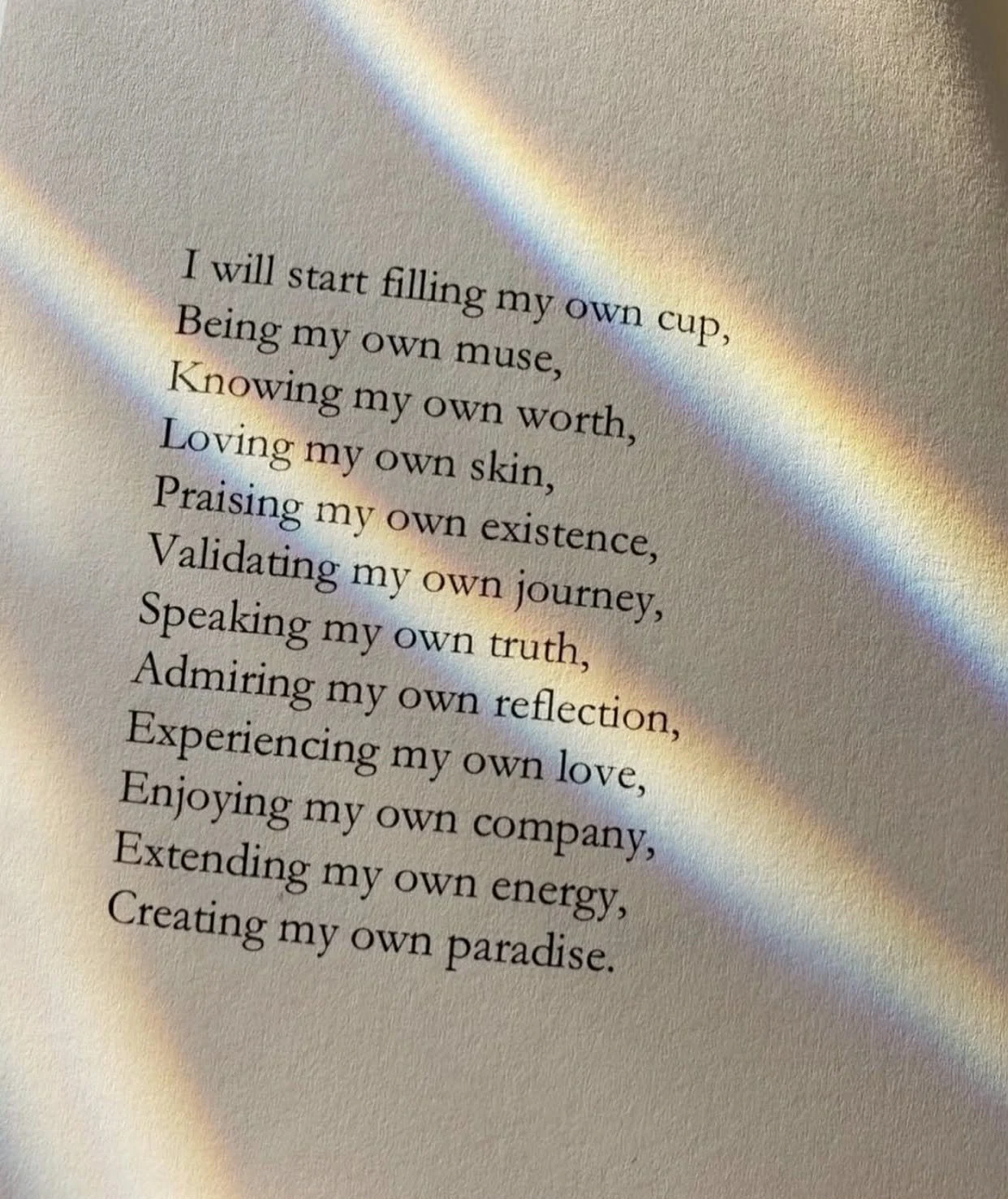 A poem written on paper with rainbow-colored light beams crossing over it.