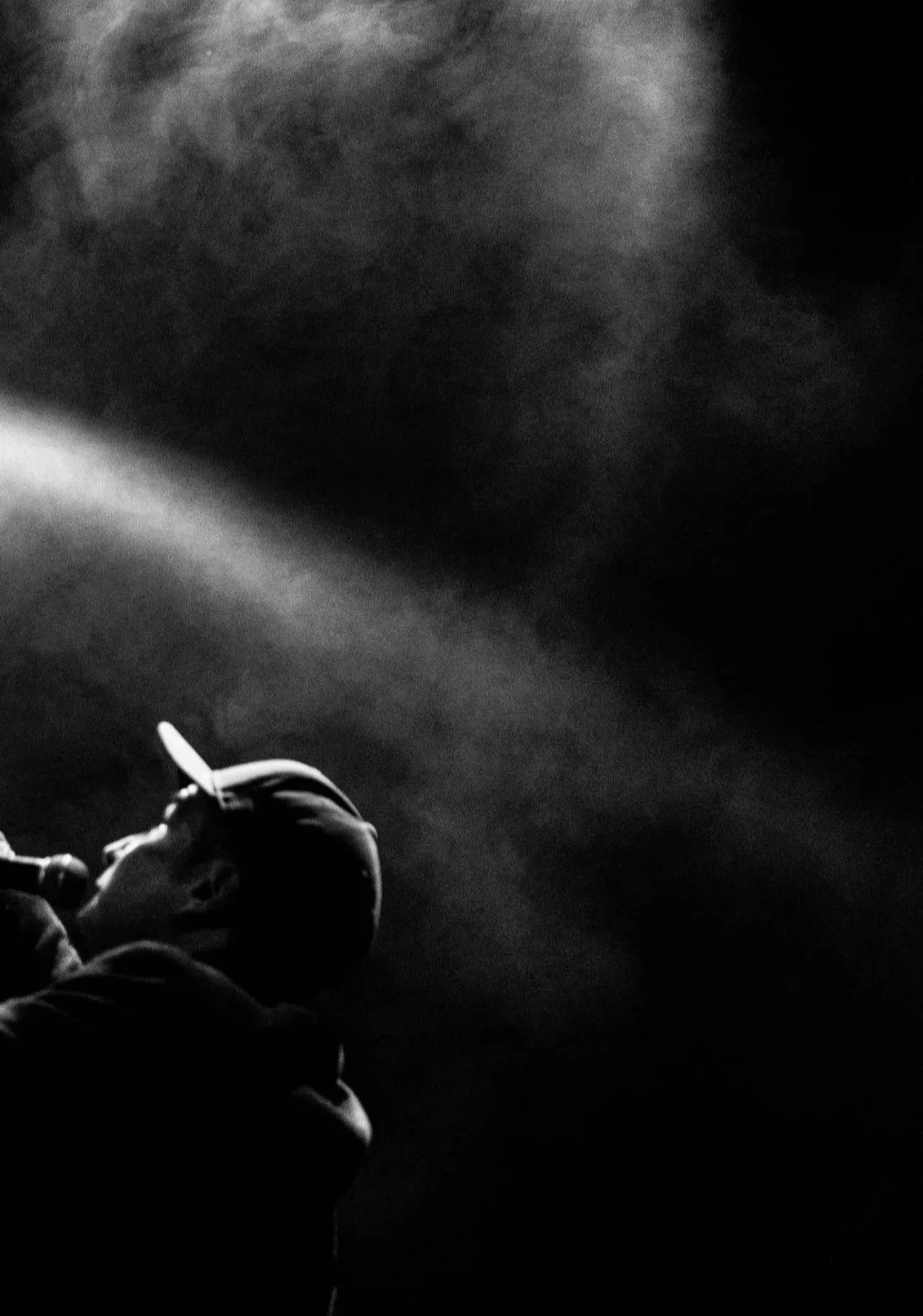 Silhouette of a person vaping with vapor clouds in the air, in black and white.