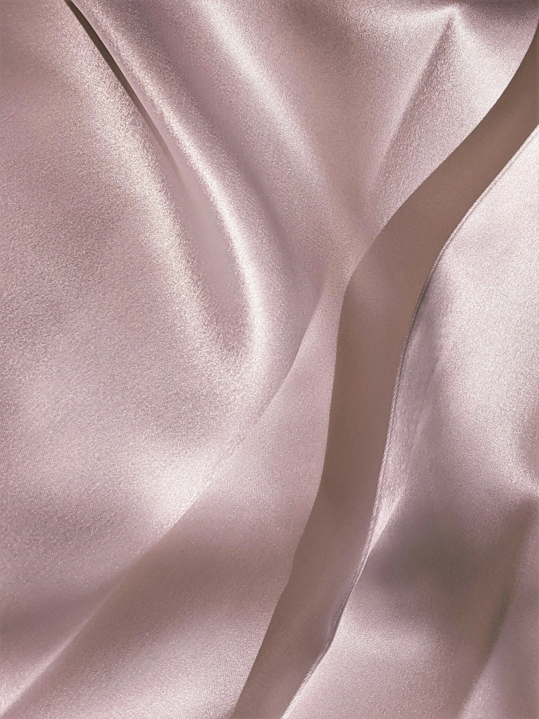 Close-up of shiny pink satin fabric with smooth, flowing texture and soft folds.