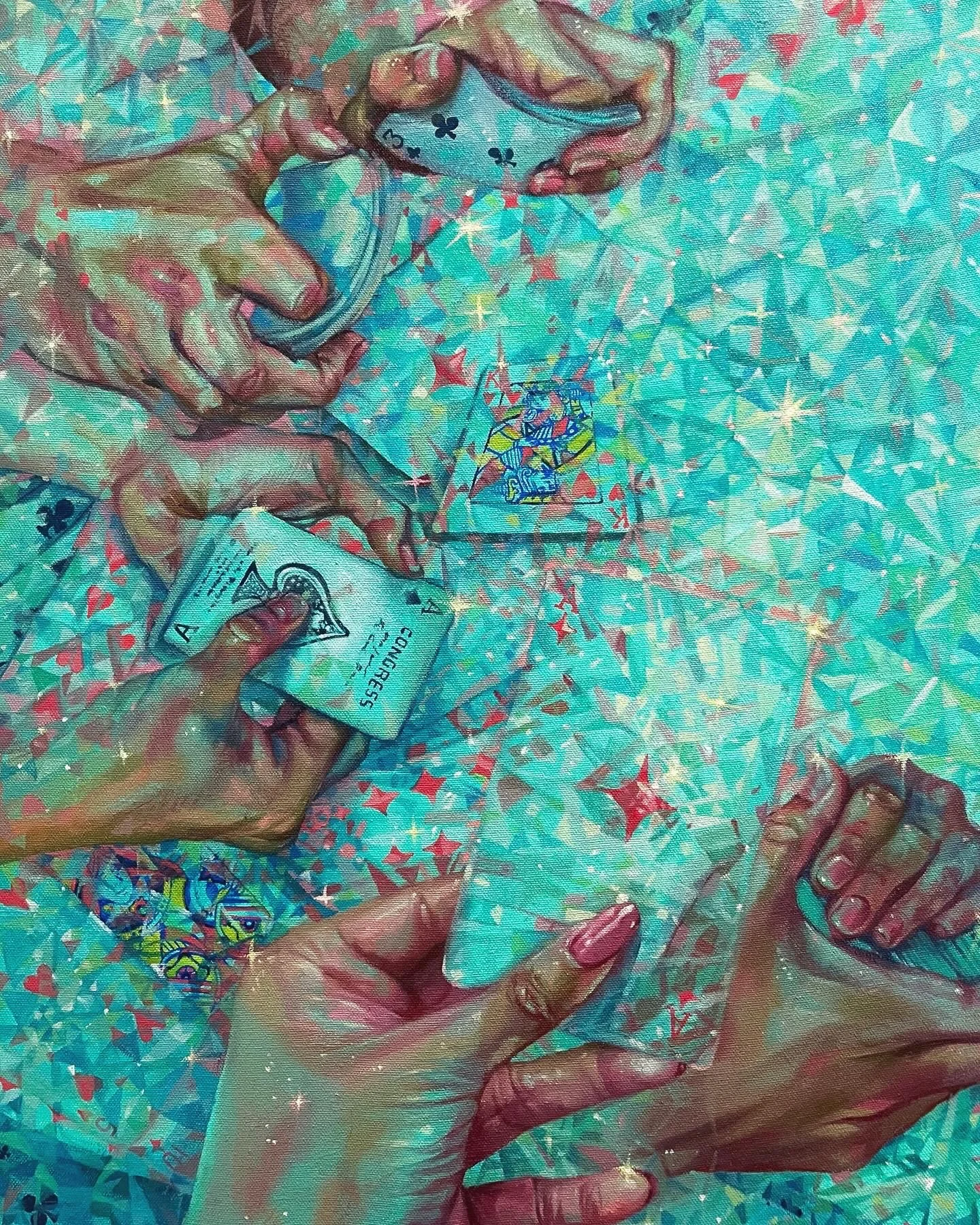 Four hands playing a card game at a table covered with colorful confetti and a lighthouse-themed centerpiece.