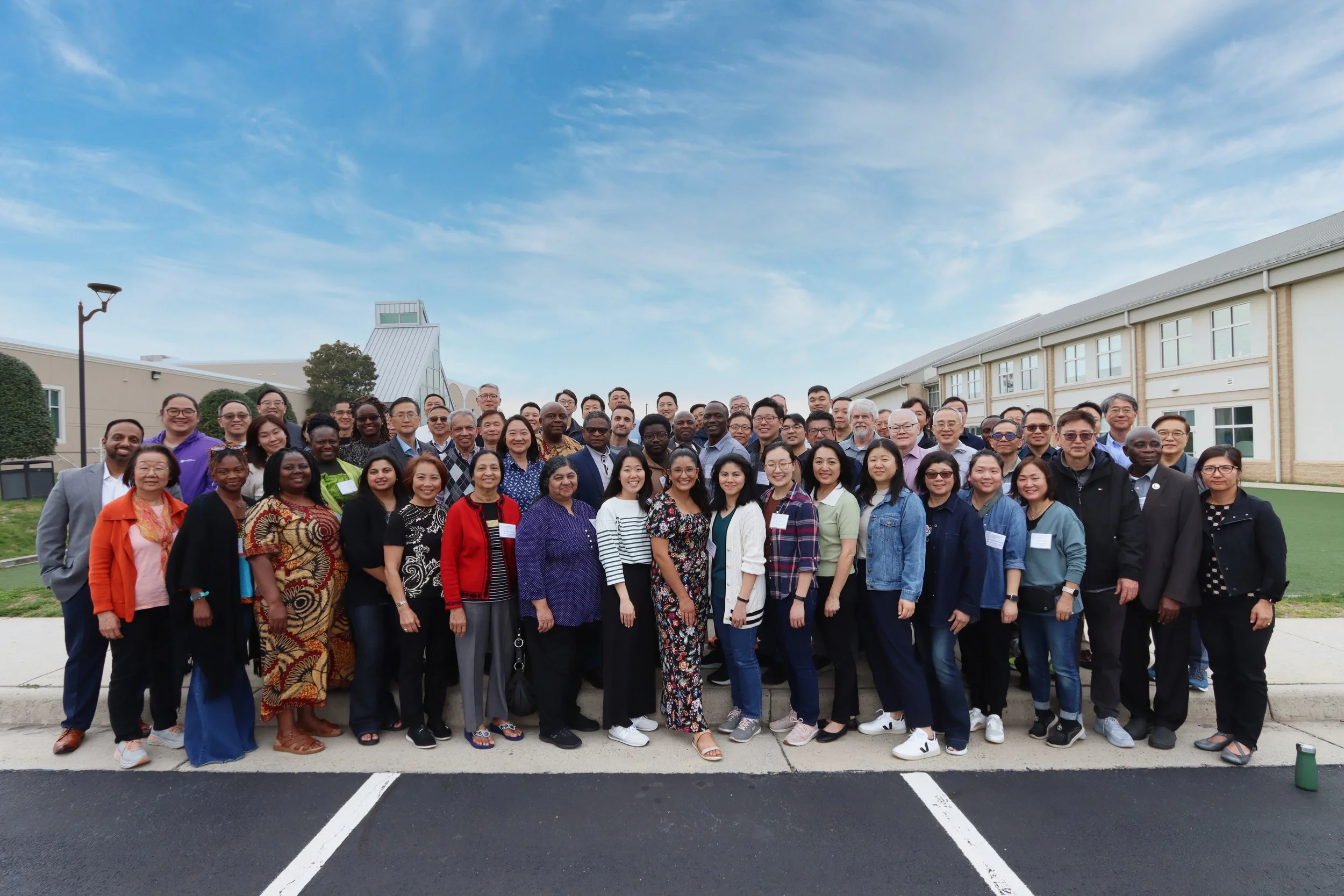 A large group of people standing in front of a church. They are from different ethnic backgrounds.