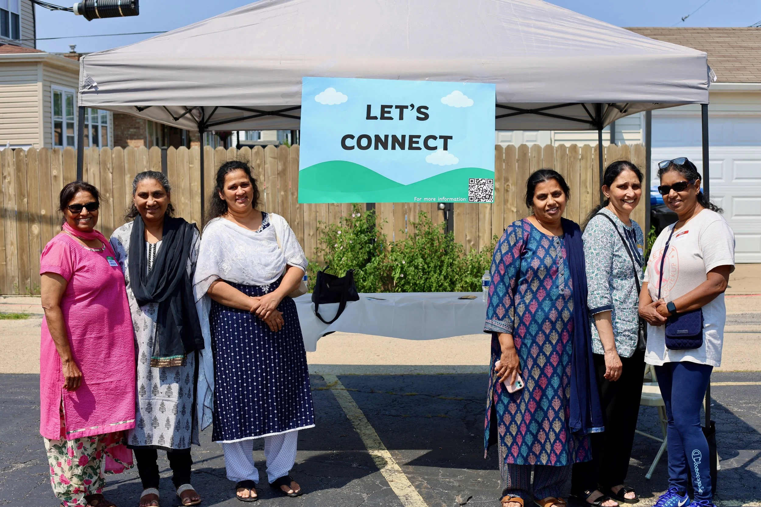 A group of Indian women standing together at a church event in a parking lot