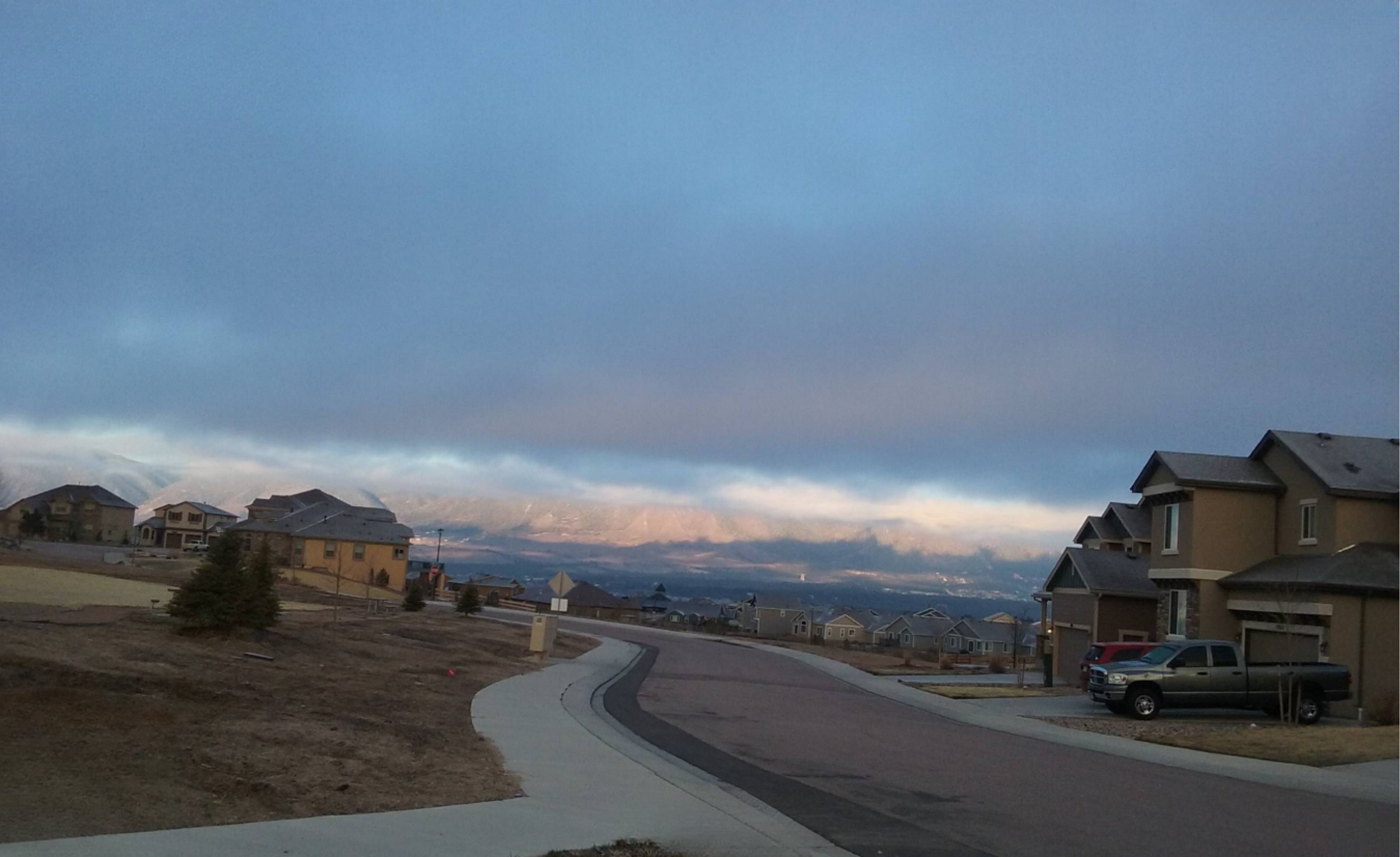 a monument colorado neighborhood street with mountains in background at sunset