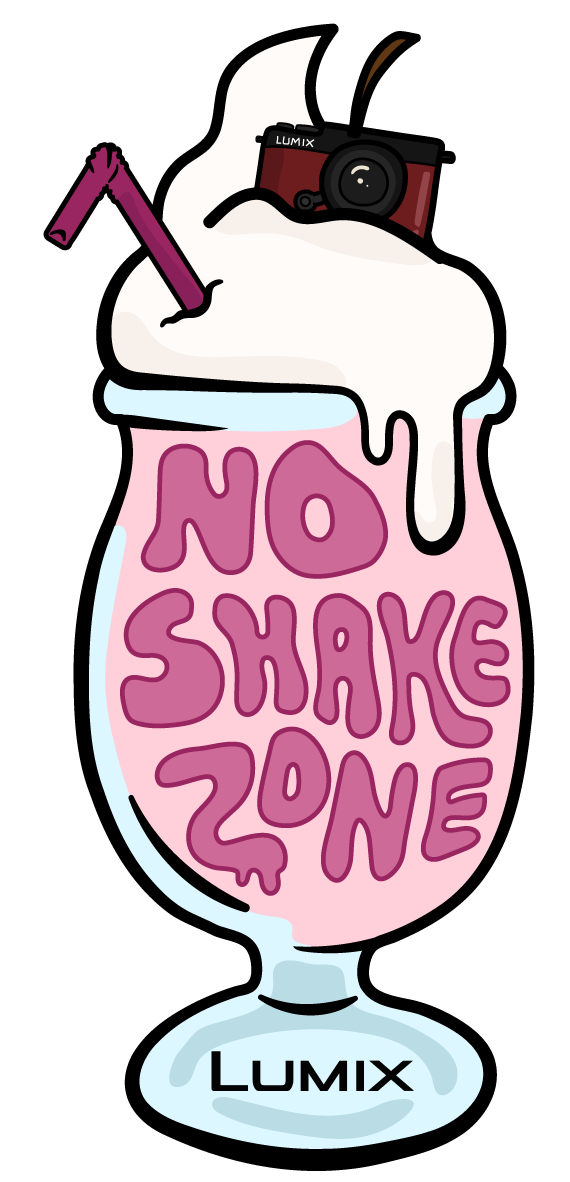 Colorful graphic of a milkshake glass with the words 'No Shake Zone' written inside the pink liquid. The milkshake has white whipped cream on top, a purple straw, and a camera resting on the whipped cream.