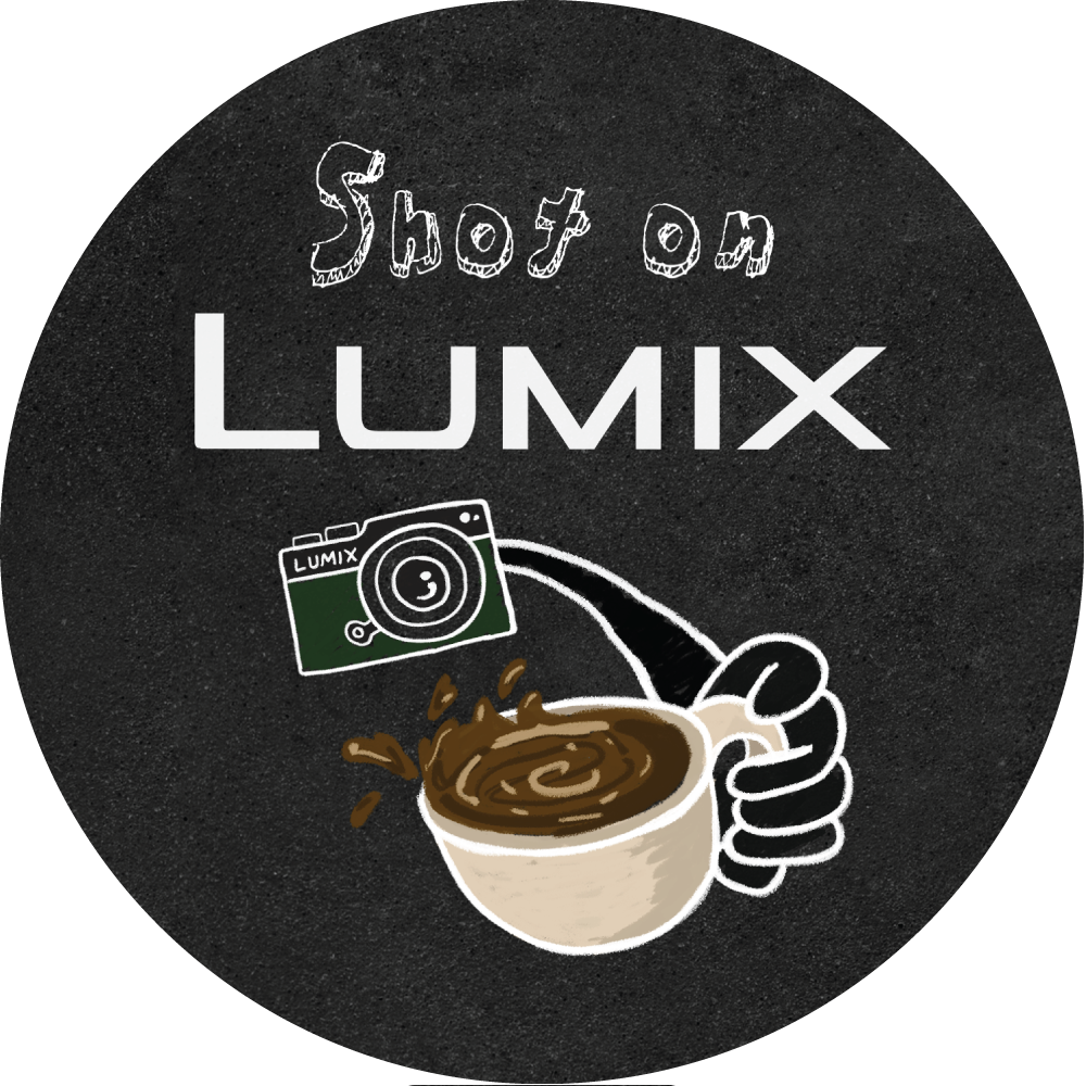 Design with the text "Shoot on LUMIX" above a white hand holding a steaming coffee cup, with a green LUMIX camera icon nearby on a black circular background.