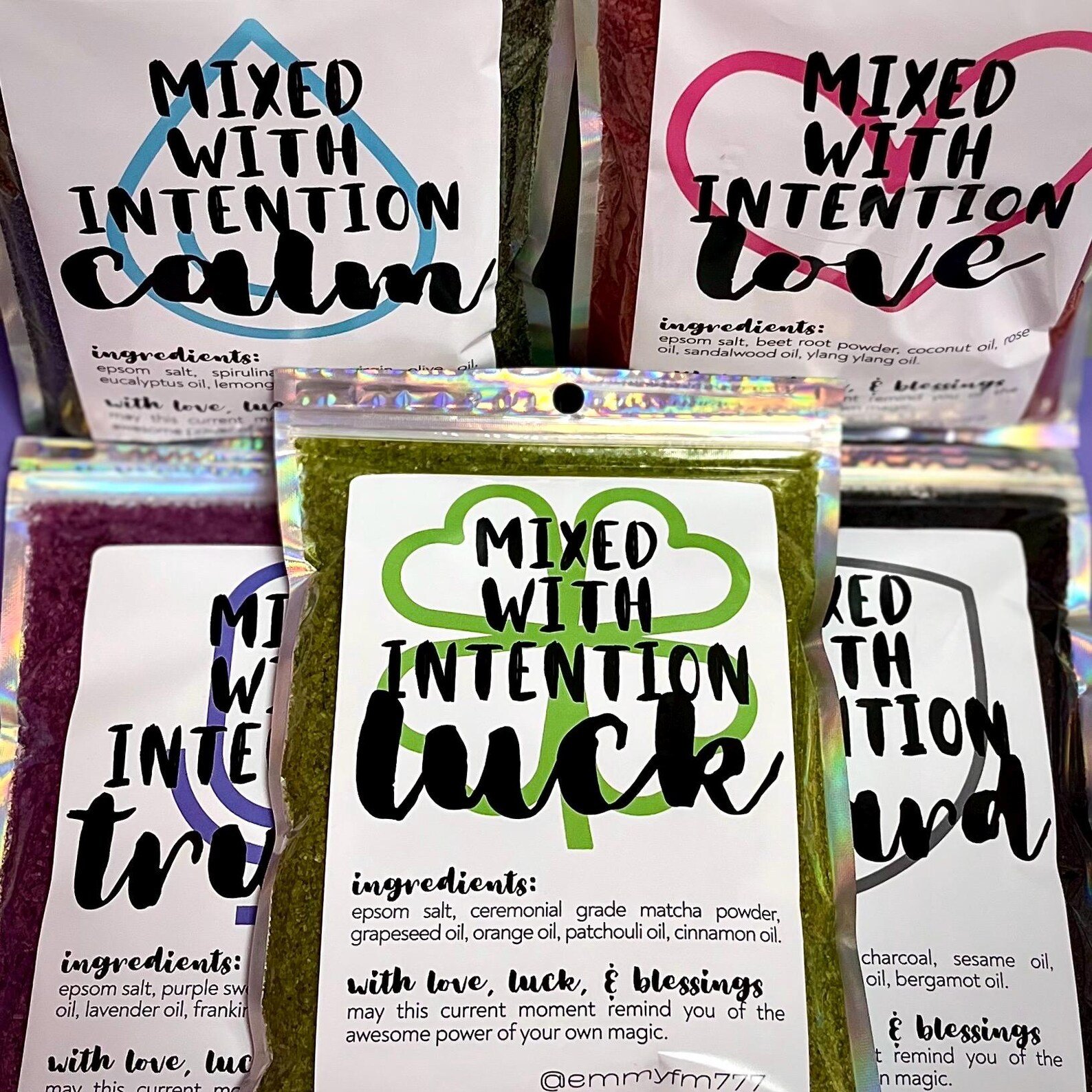 group of bath sachets with bold, colorful labels reading ‘mixed with intentions’ in various themes like calm and luck, displayed on a white background.