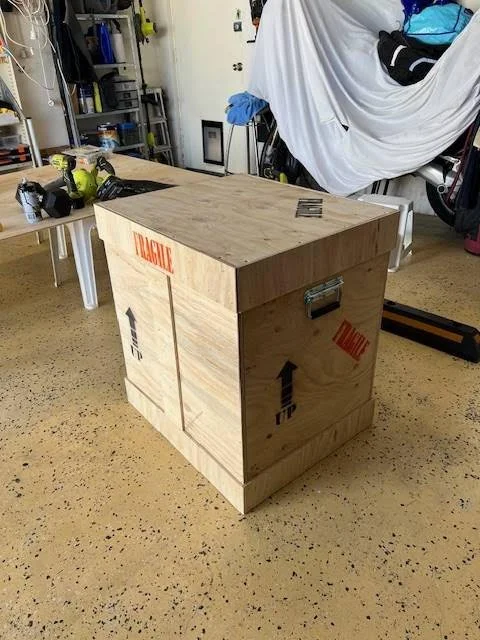 Wooden shipping crate with 'Fragile' labels in a garage or workshop, surrounded by tools and equipment.