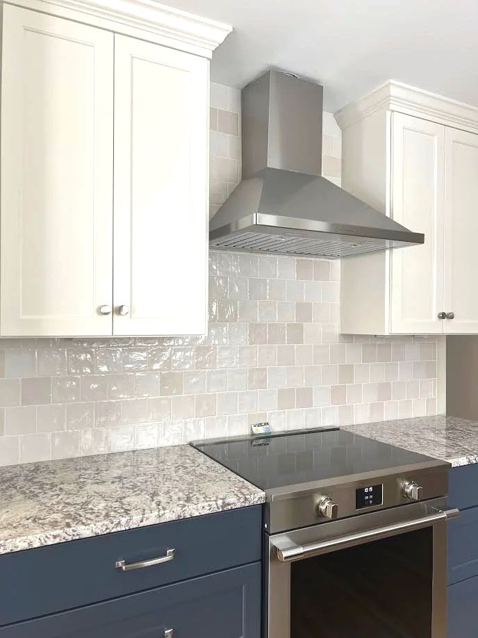 Kitchen with white upper cabinets, a stainless steel range hood, granite countertops, a black electric stovetop, and blue lower cabinets.