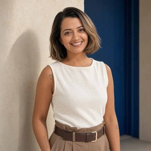 Woman in white top standing next to wall.