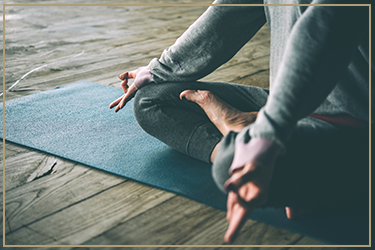Person practicing yoga or meditation on a blue mat in a peaceful indoor setting