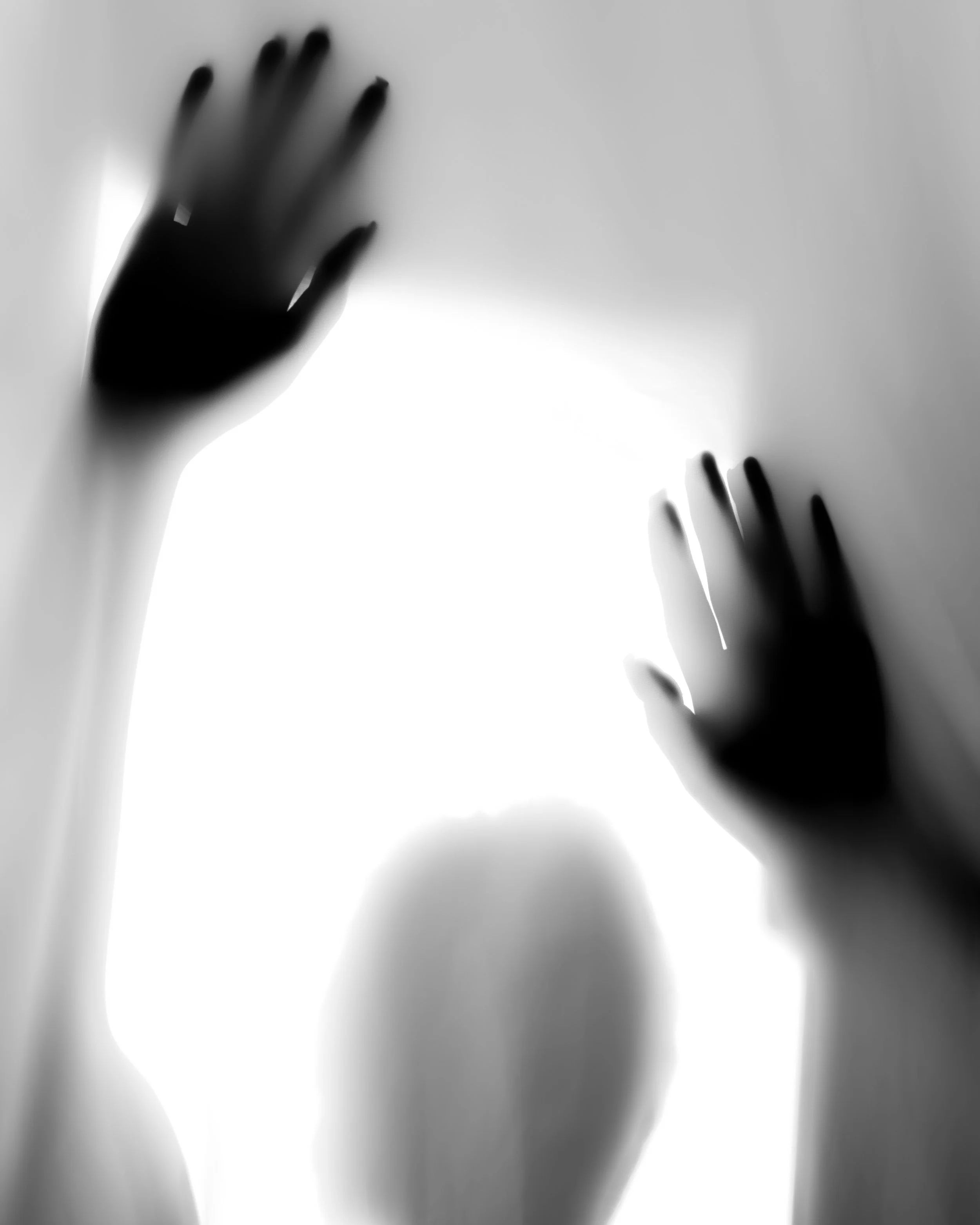 Silhouetted hands pressing against a translucent surface, creating a ghostly effect.