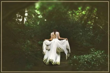 A person wearing a white dress hanging upside down from branches in a lush green forest.