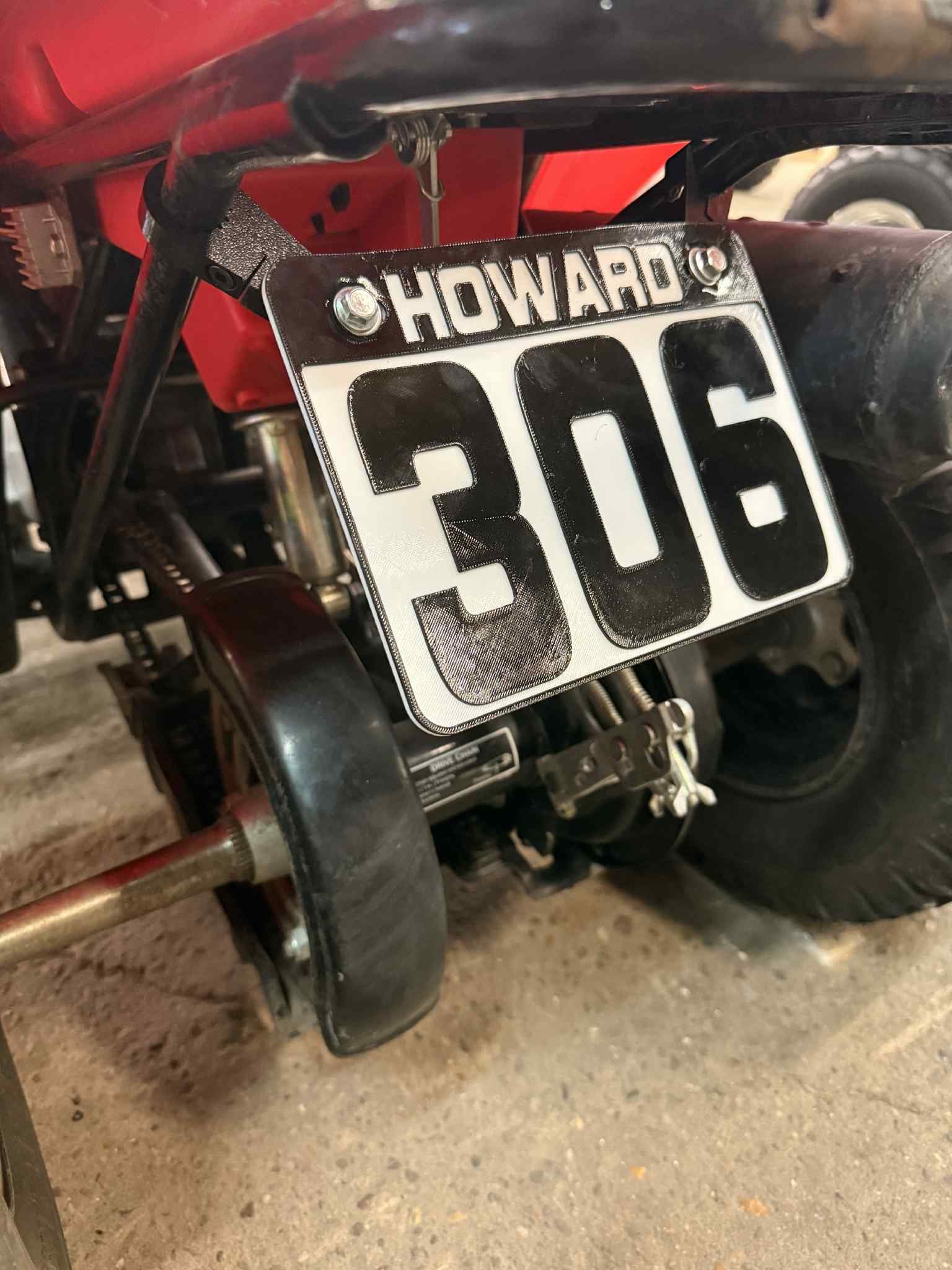 Close-up of a red Honda off-road vehicle with a black-and-white number 506 plate and exposed suspension components.