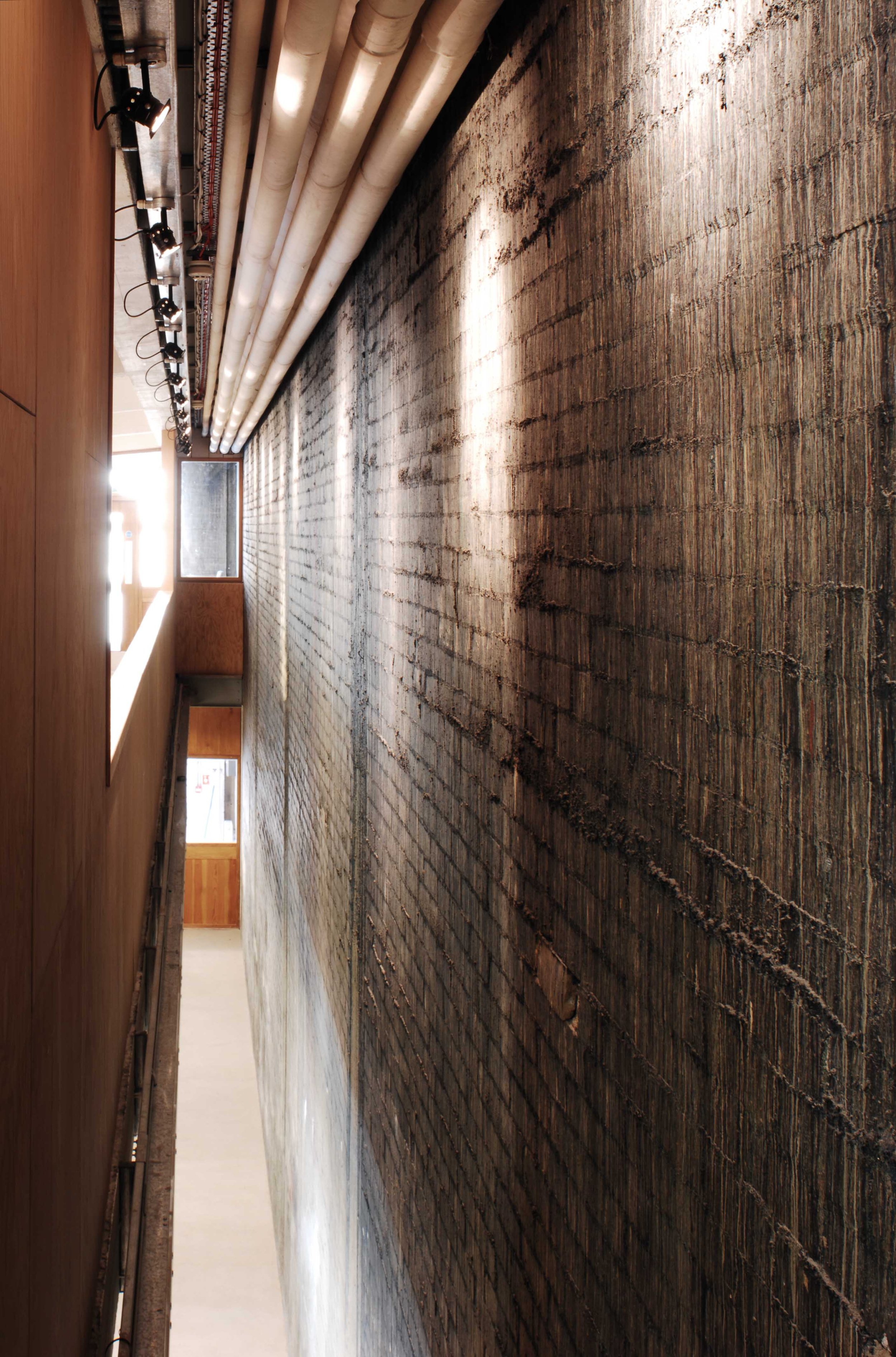 Empty hallway with wooden paneling, brick wall, and track lighting along the ceiling.